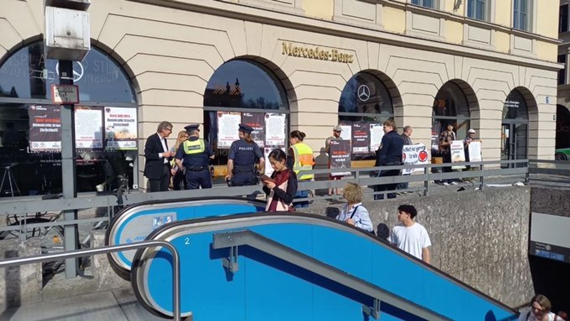 Menschen kleben Plakate an ein Mercedes-Benz-Gebäude