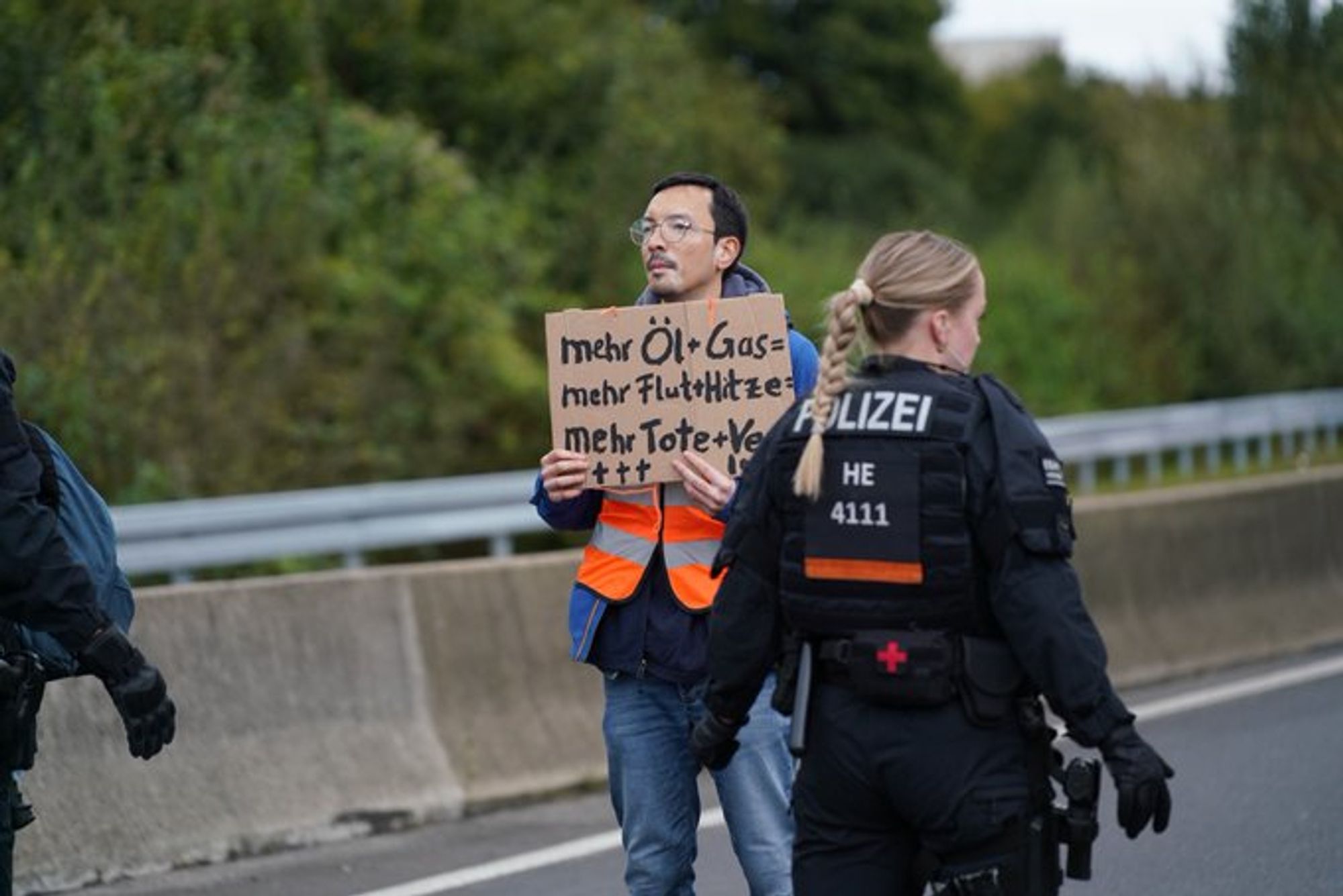 Mensch hält Schild hoch: "mehr Öl + Gas = mehr Flut + Hitze = mehr Tote + Verletzte