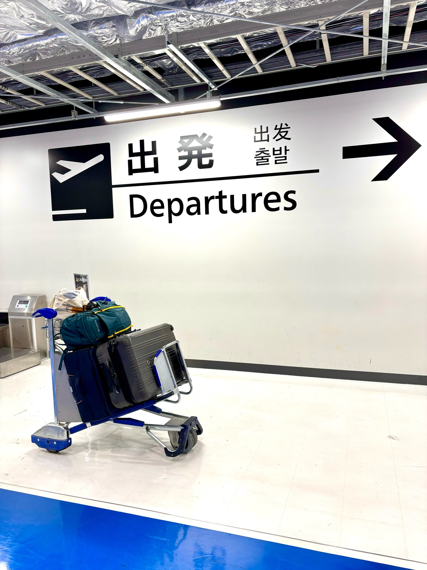 成田空港の出発ゲートサイン前に置かれた荷物満載のカート