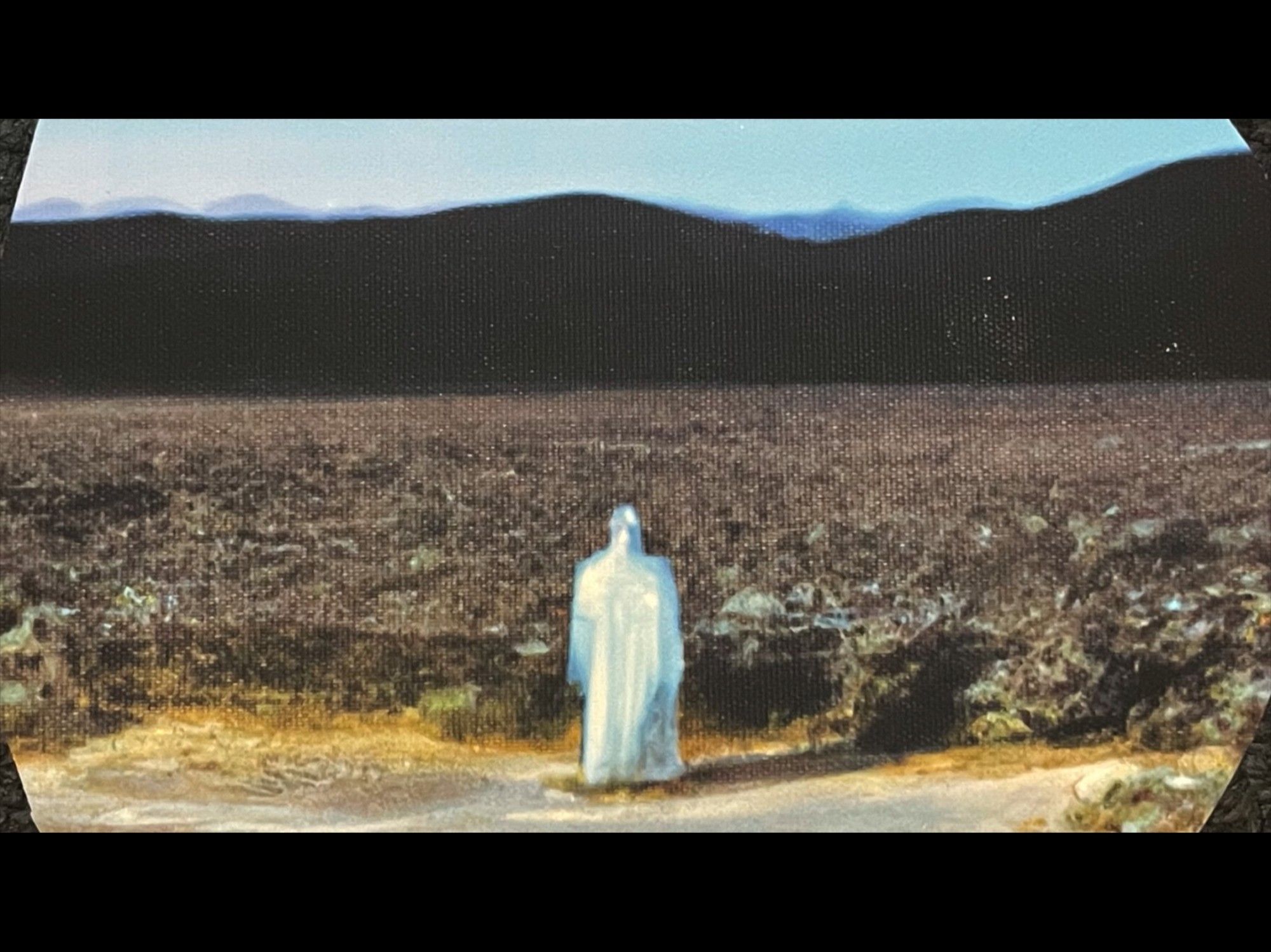 Ominous painting of a white cloaked figure standing before the high desert