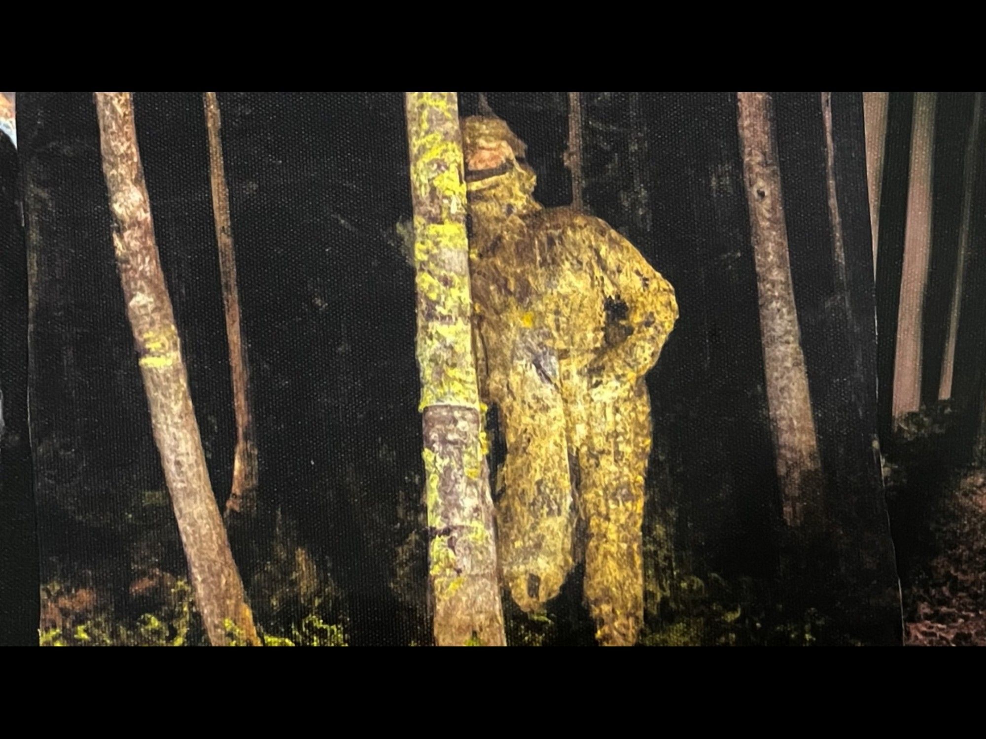 A painting of an all-yellow figure with rough texture standing in a weird pose by some trees at night