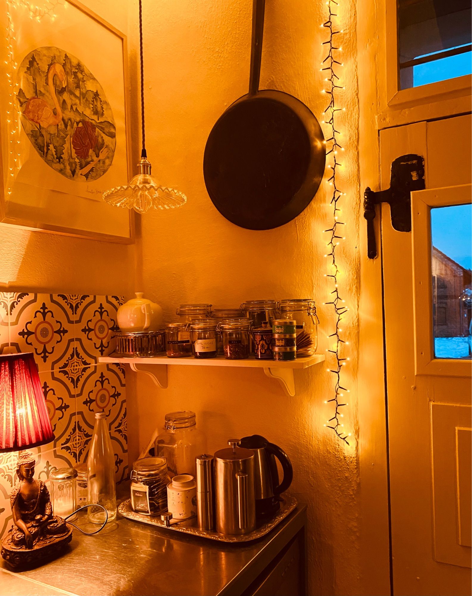 Corner in our kitchen, with fairy light, a buddha lamp, coffee, kettle and tea supplies.