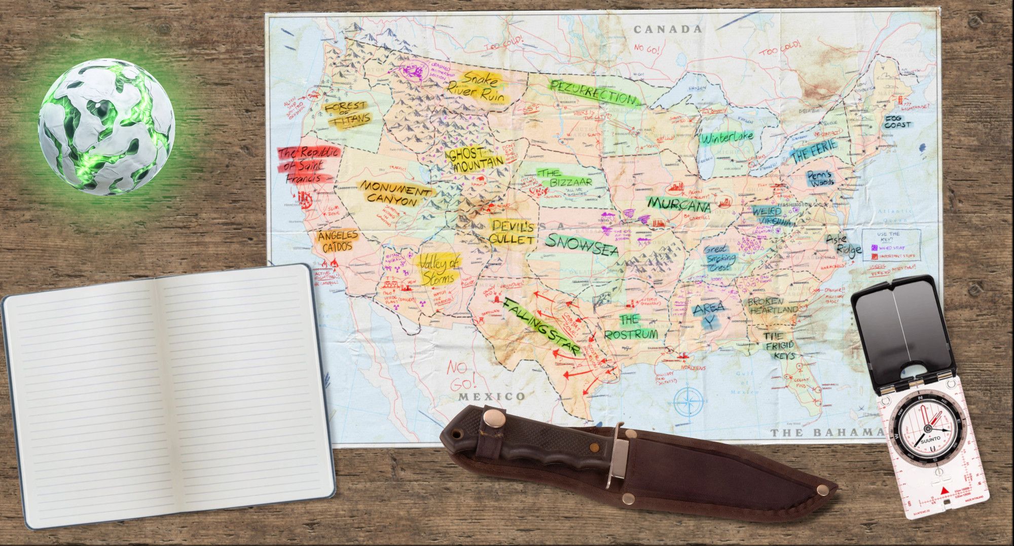 A stylized map of the United States from The Last Caravan is against a wood background, surrounded by a compass, a hunting knife in a sheath, an open blank-lined journal, and a glowing green white sphere shot through with glowing green cracks.