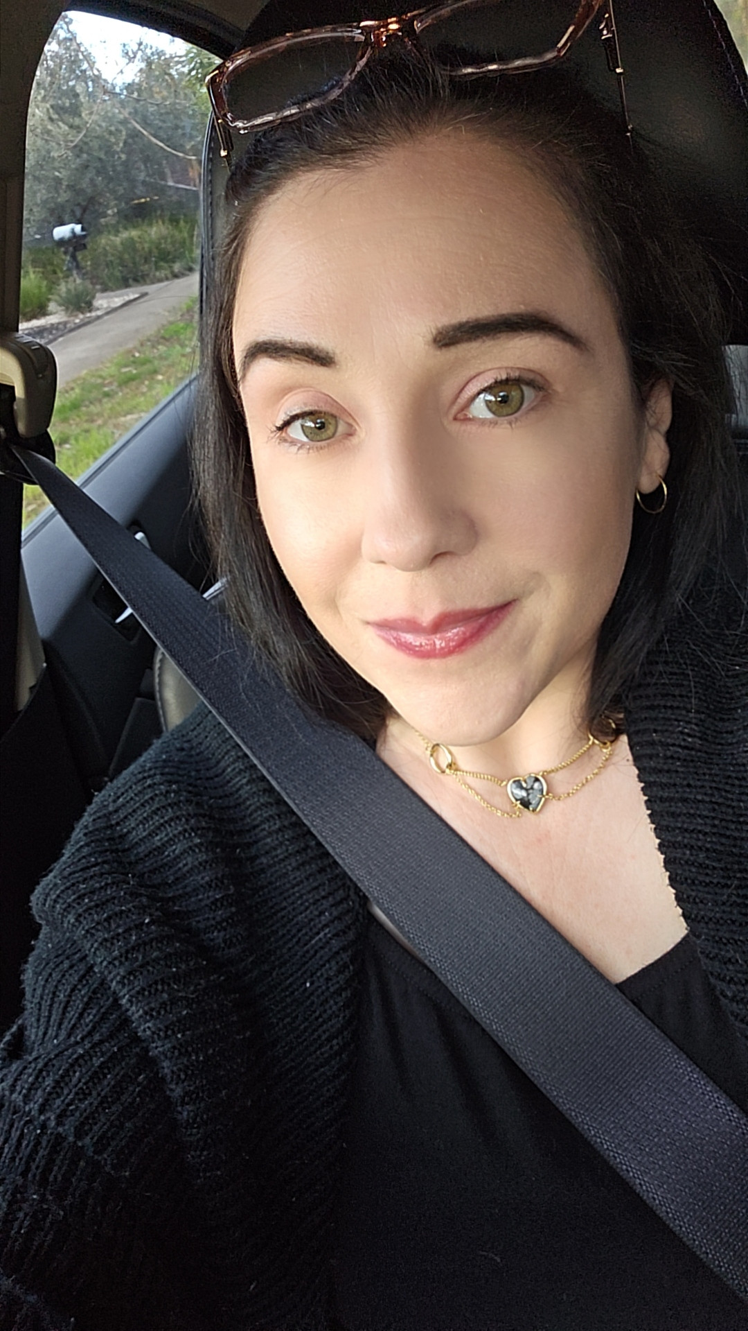 Picture of Kat sitting in a car. Black top and cardigan. 
