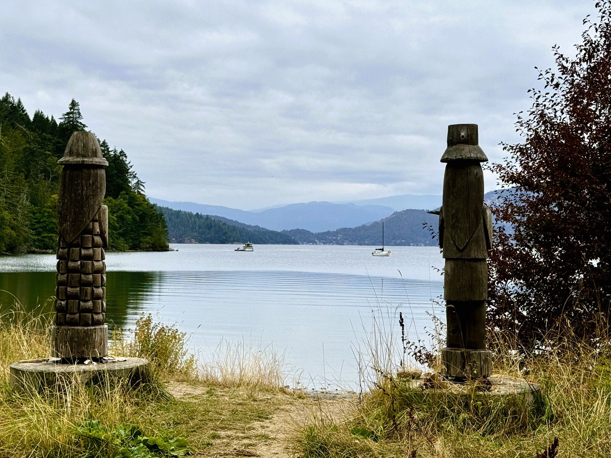 A view between two wooden carvings of a lake with mountains in the background.