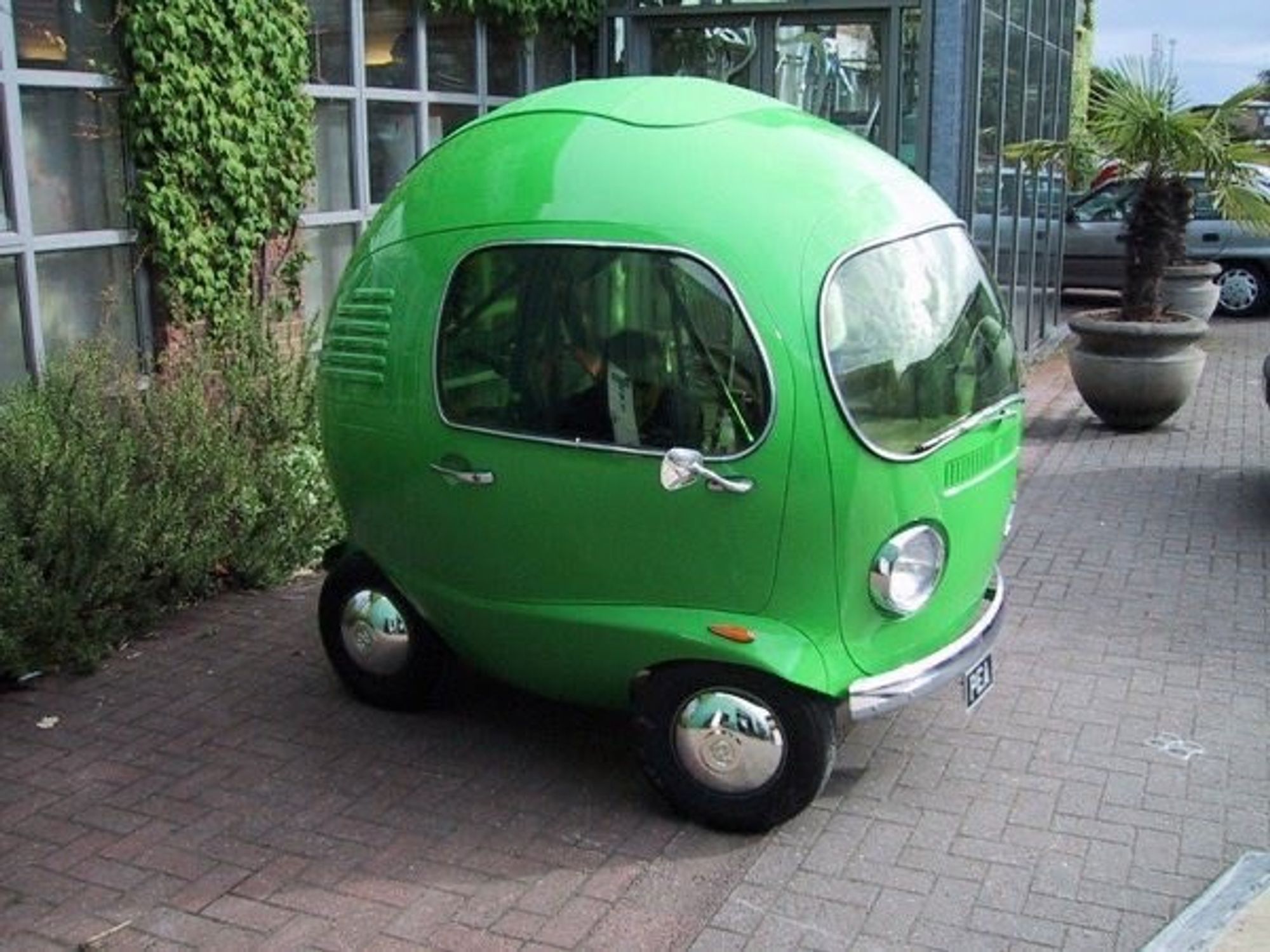 A tiny green Volkswagen car which basically looks like a metal pea on wheels