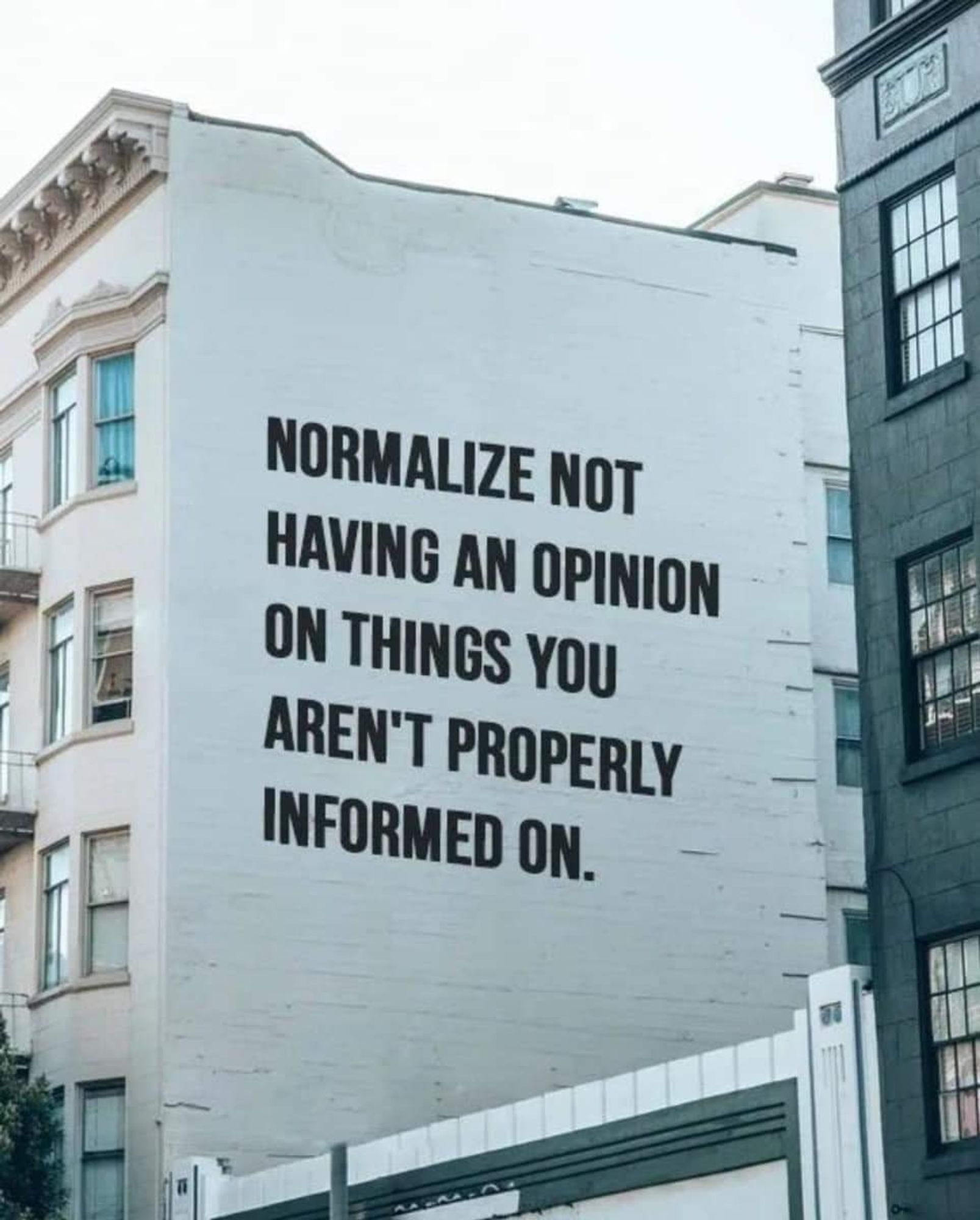 The side of a building where someone has added 'normalize not having an opinion on things you aren't properly informed on'