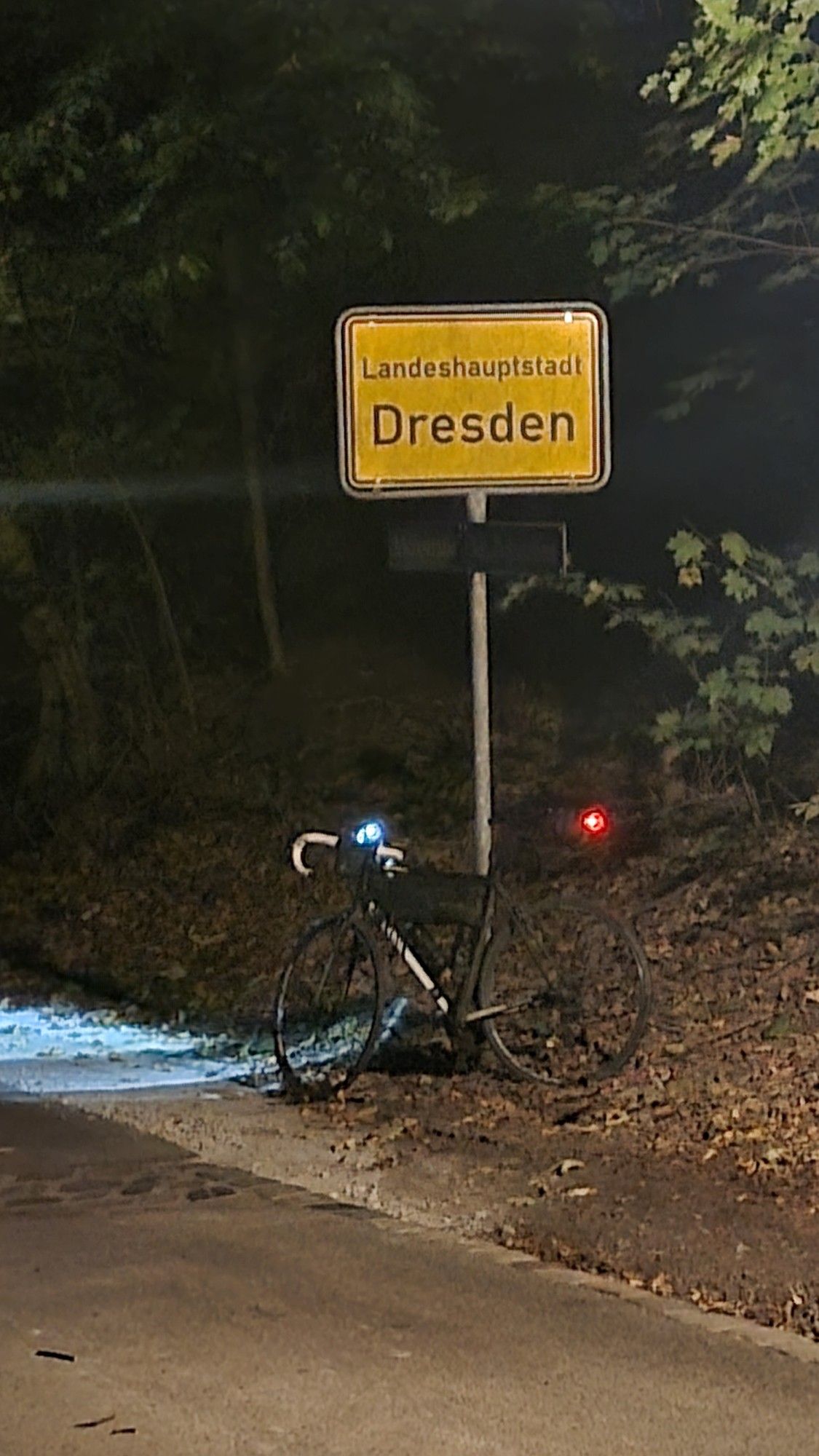 Mein Rad vorm Ortsschild von Dresden. Dunkelheit, Licht einer Laterne