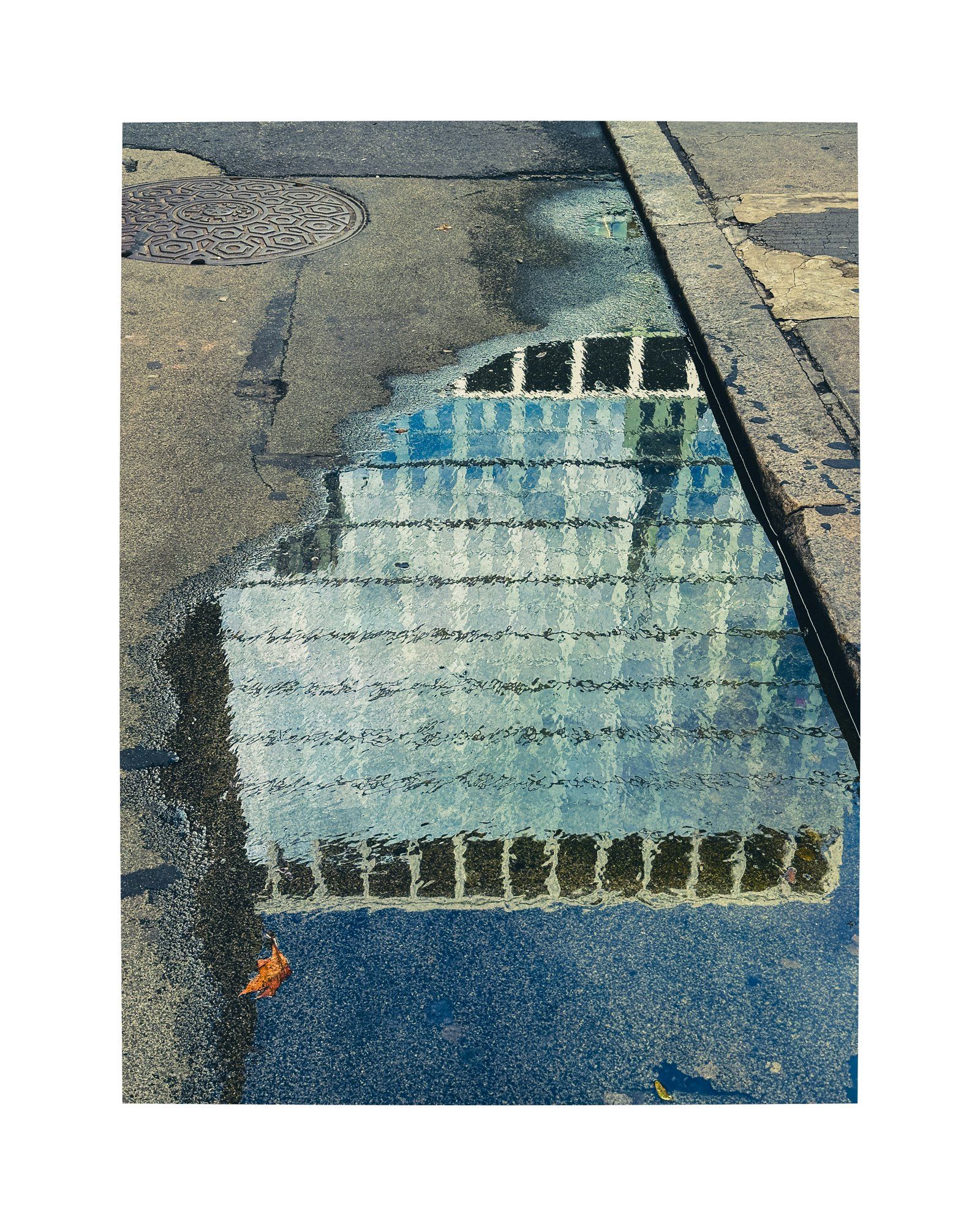 A city building reflected in a windswept puddle