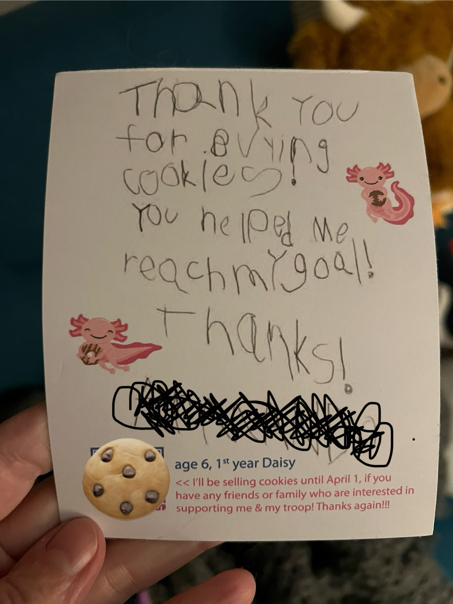 The back of the thank you card. It is decorated with two more pink axolotls, each holding a cookie. 

There is a handwritten note by a young person still perfecting the craft of handwriting. It says: thank you for buying cookies! You helped me reach my goal! Thanks!

Once again, for privacy reasons, I’ve scribbled over the scout’s name & put a cookie over the QR code on the bottom left. 