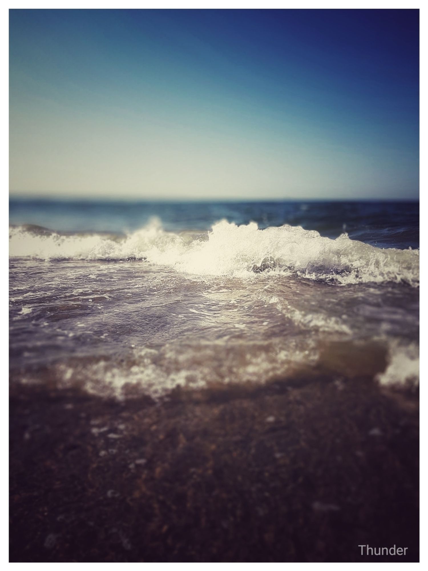 Auf dem Foto sieht man das Meer unter blauem Himmel in verschiedenen blau Tönen von dunkel über türkis zu hellblau/ weiss. Das Meer rauscht mit einer kleinen Welle über den Strand, schlägt schaumig auf. Dahinter ist es weit und blau wie der Himmel. Das Foto ist von 2019 und wurde in Renesse aufgenommen. Mein letzter Strand Urlaub 🥺