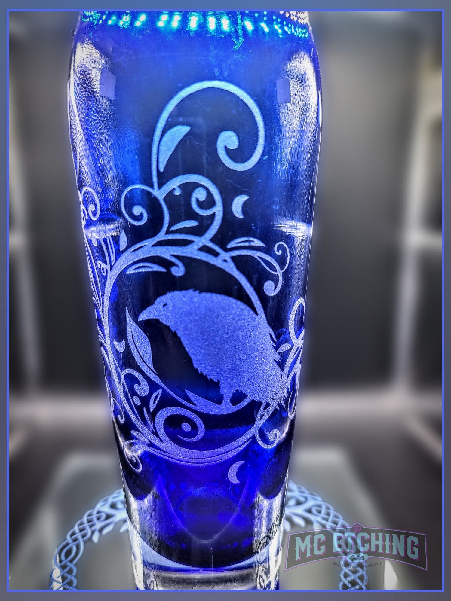 blue glass vase etched with a raven and filigree vine design