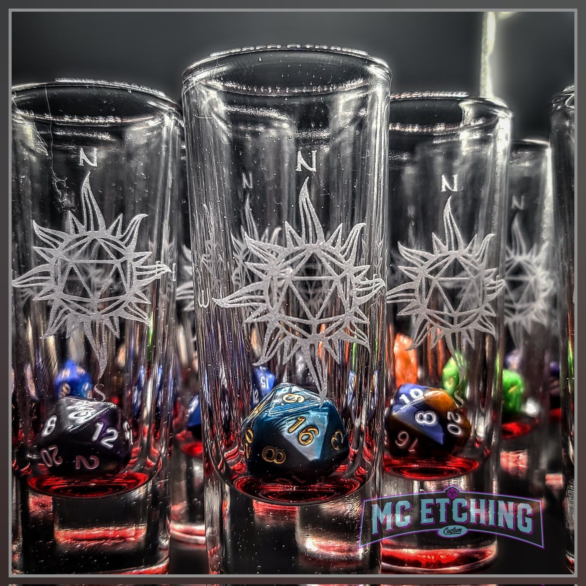 rowes of tall cordial glasses each etched with a d20 dice compass rose design and containing a resin D20 die at the bottom