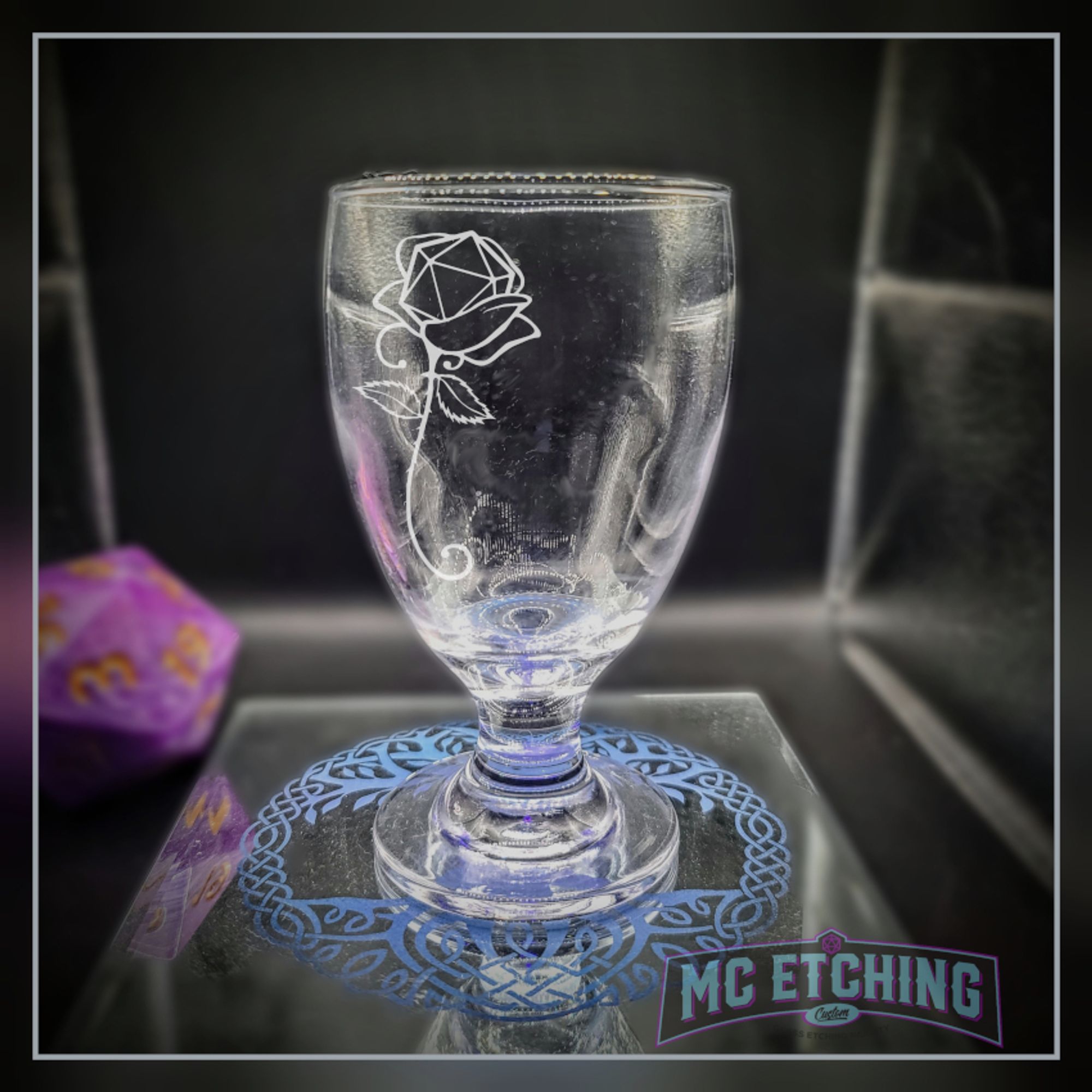 Small goblet with the image of a rose whos bloom contains a d20 gaming die.