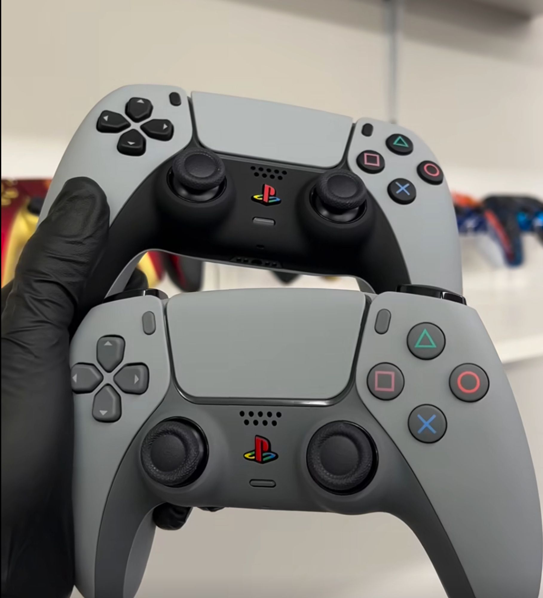 a latex-gloved hand holding two Playstation 5 controllers