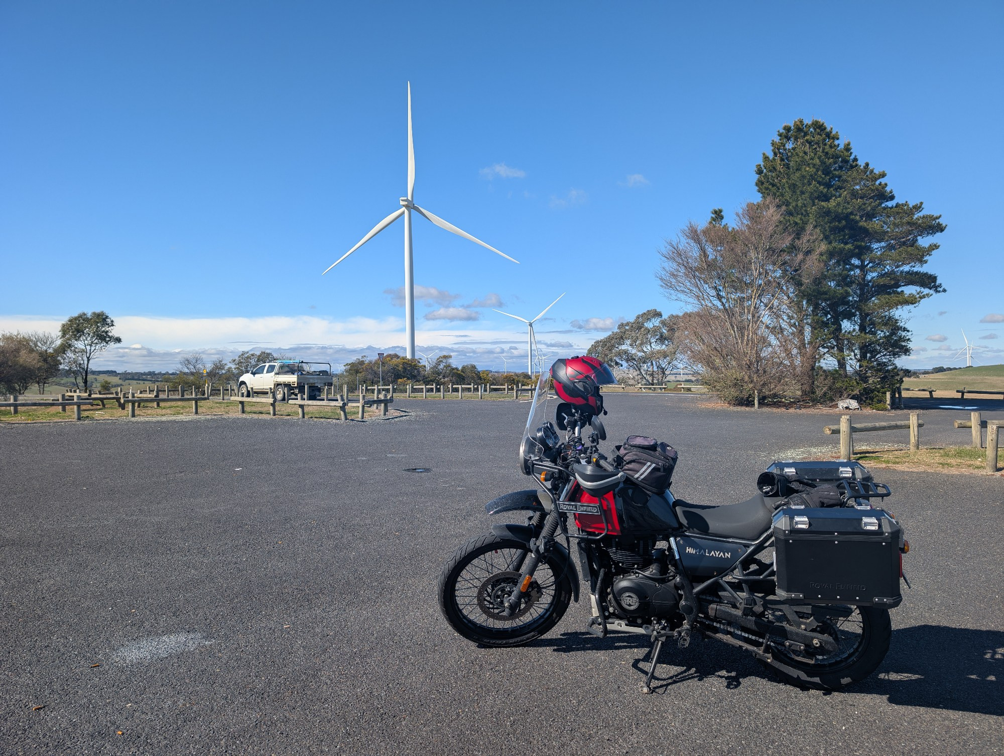 A Himalayan 411 motorcycle in front of some wind turbines.