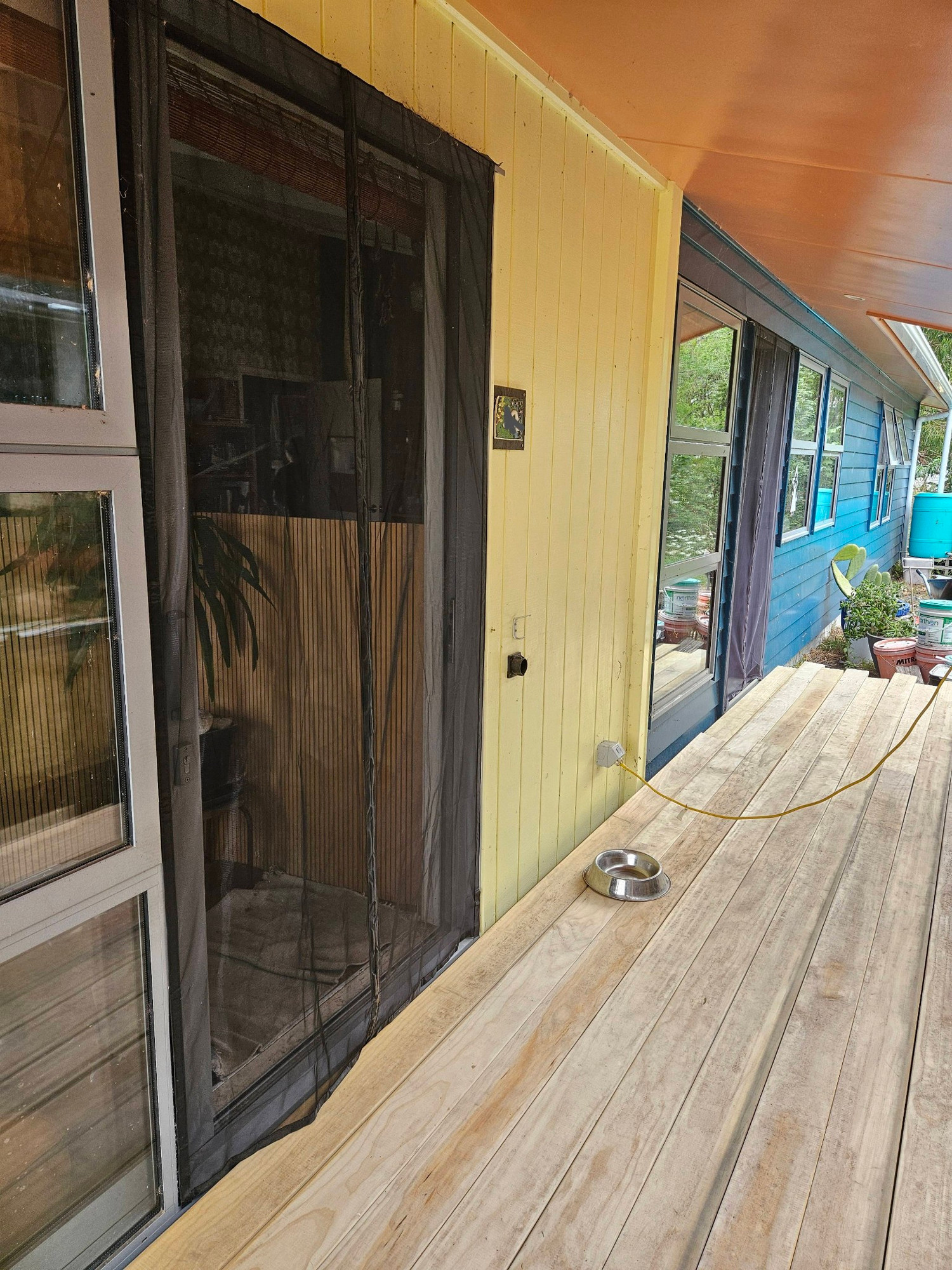 Unfinished deck under a verandah on a yellow, pink and blue house