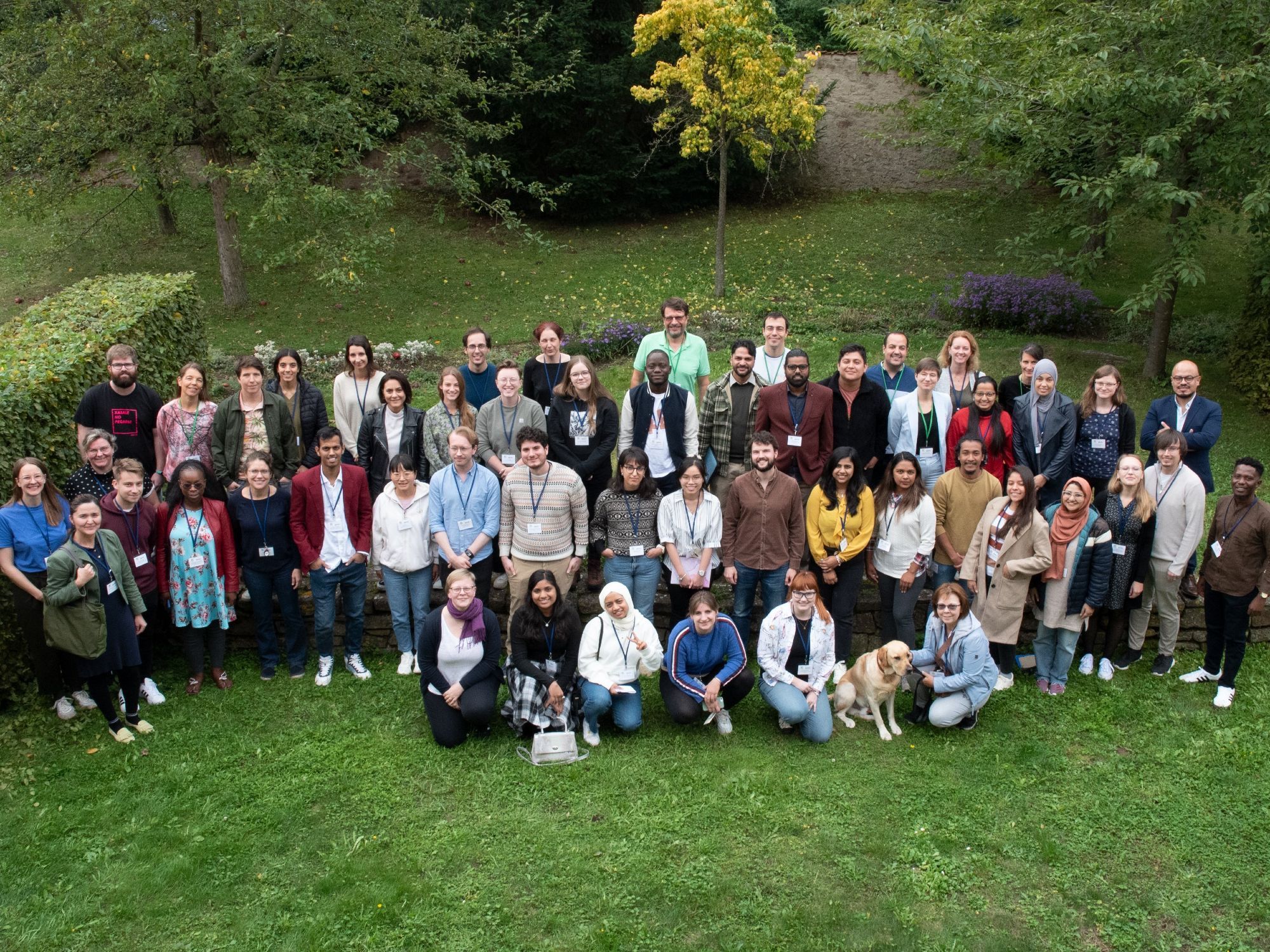 A group photo of a bunch of scientists standing together with a green background