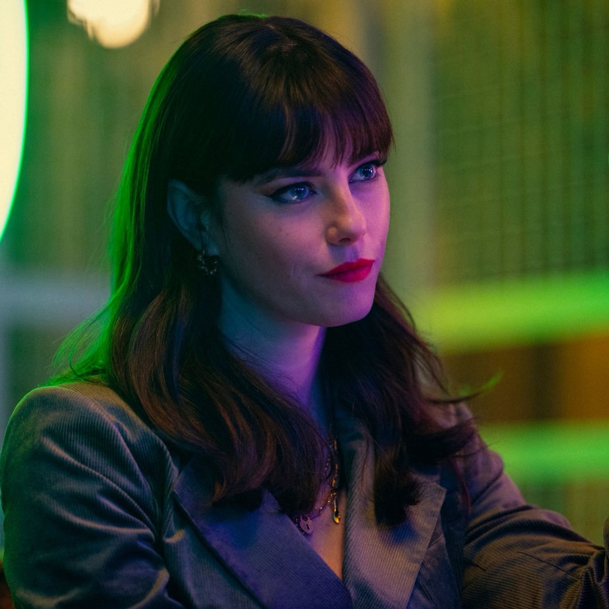 An image of Susie Glass from the limited series “The Gentleman”
She is a white woman with blue eyes, dark shoulder length hair, and a bold red lip.