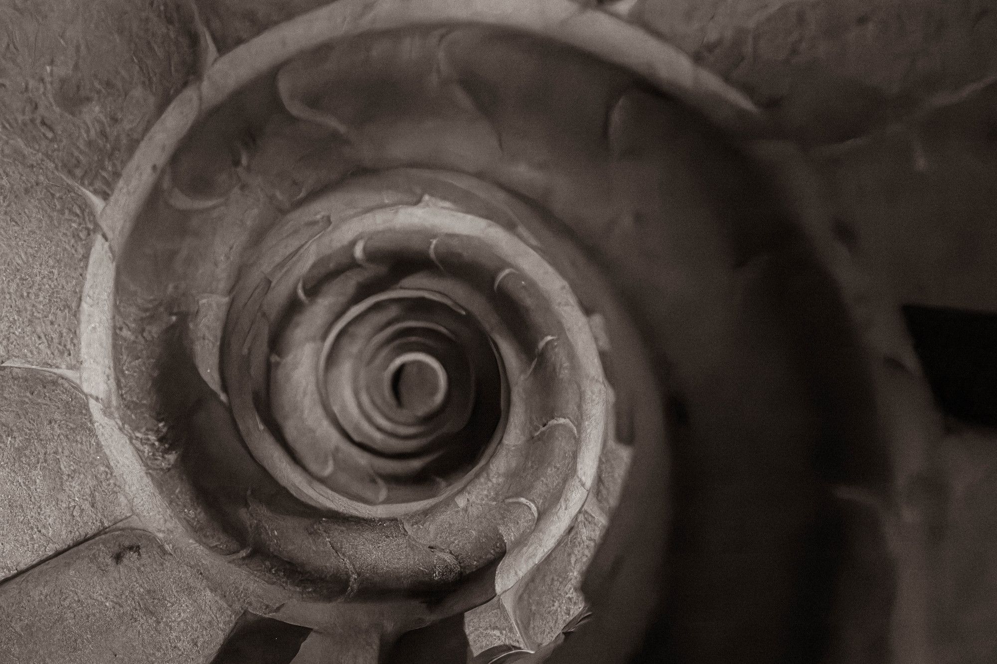 Looking down Gaudi's spiral stair within the tower of the Sagrada Familia in Barcelona, black-and-white photo.