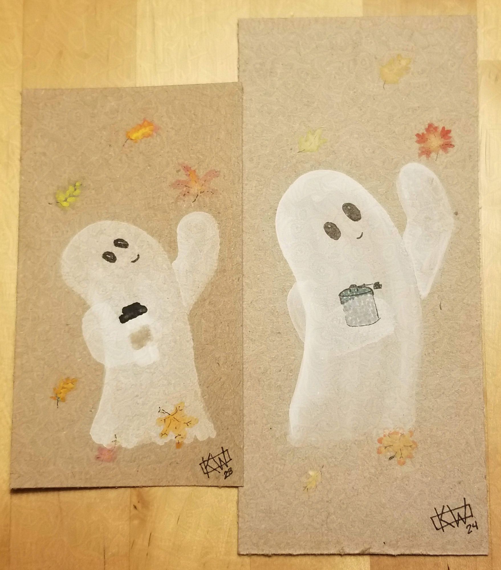 2 paintings, side by side.
Pic 1: Paint & ink on cardboard. A happy ghost is holding a coffee & reaching out toward a falling leaf. Other leaves swirl around, in the air & on the ground.
Pic 2: Paint & ink on cardboard. A happy ghost is holding a flask & reaching out toward a falling leaf. Other leaves swirl around, in the air & on the ground.