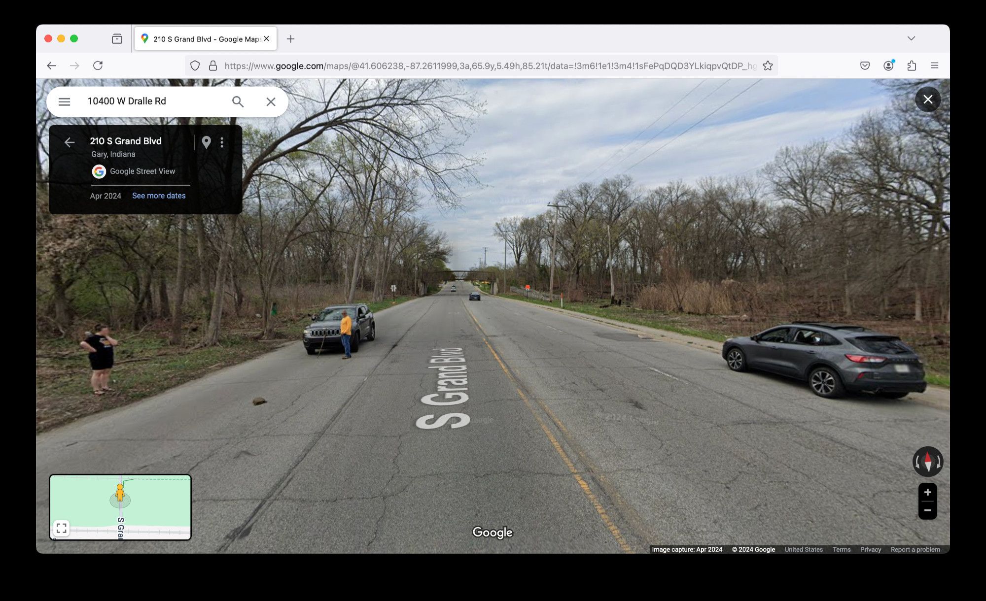 Wide shot of scene. Cars in both directions of this road are stopped. We can't quite make out why, but on the left, two passengers have exited their car and are gazing at the ground.