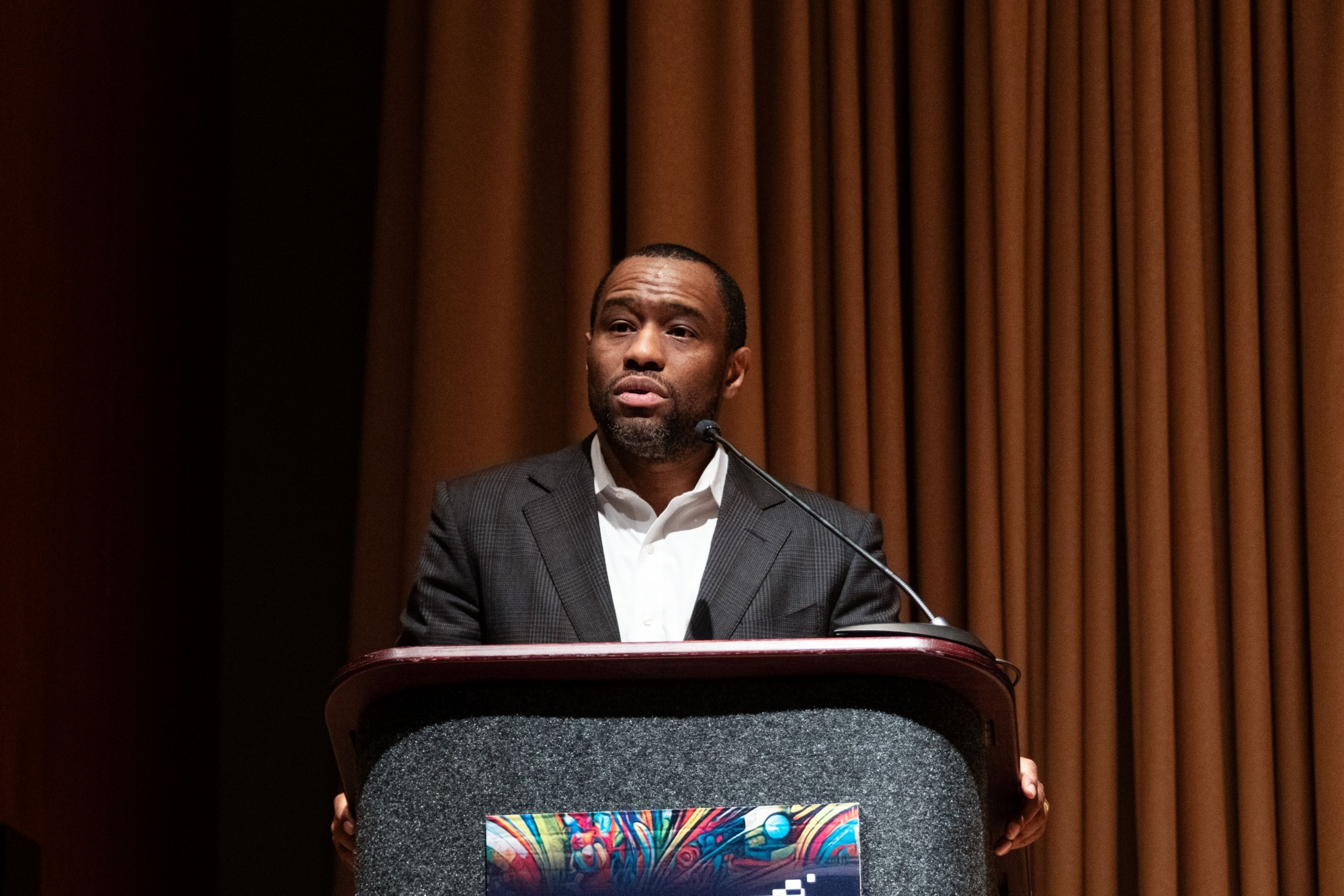 a person stands at a lectern speaking into a microphone