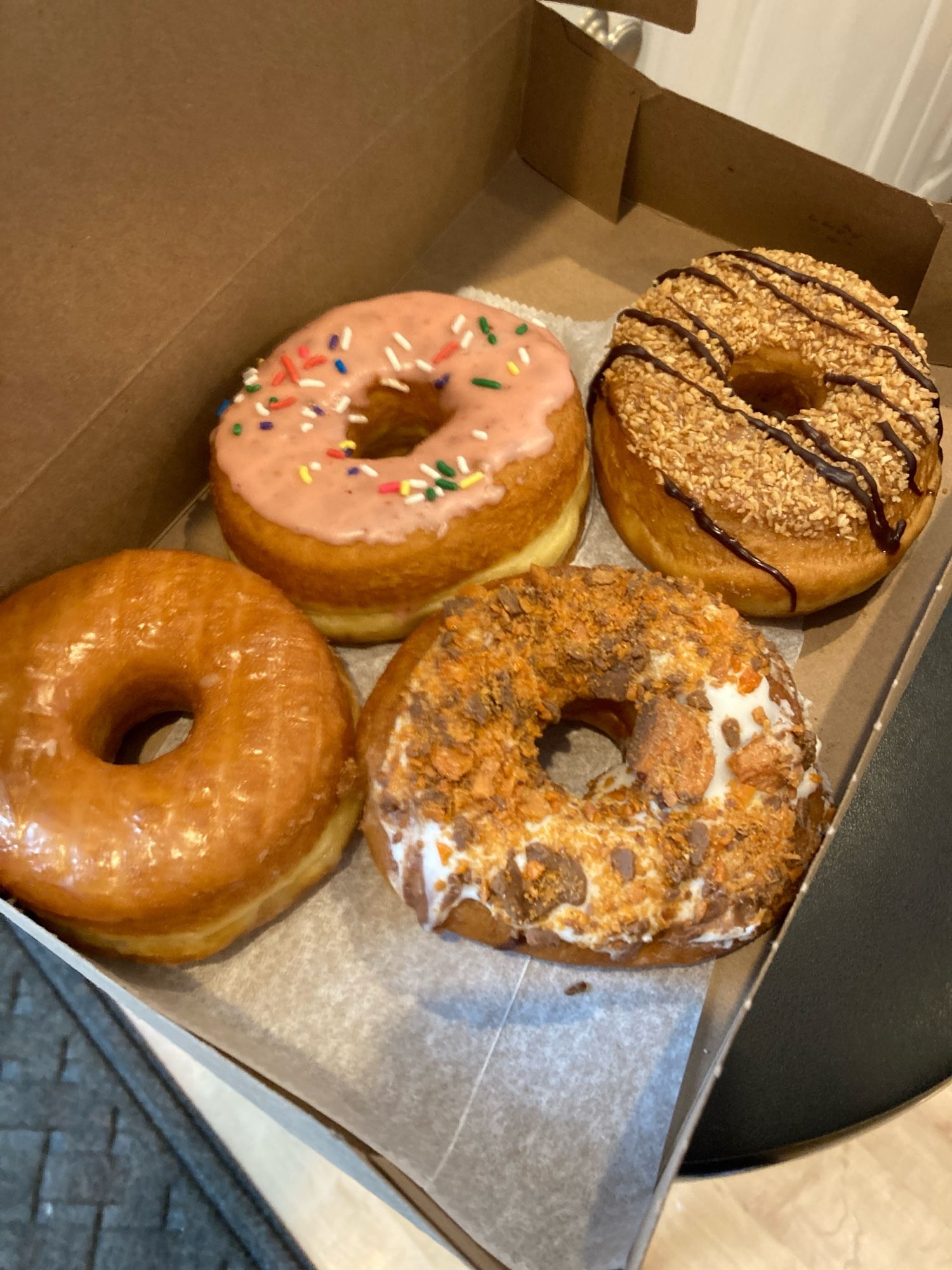 Four delicious fancy donuts in a cardboard box