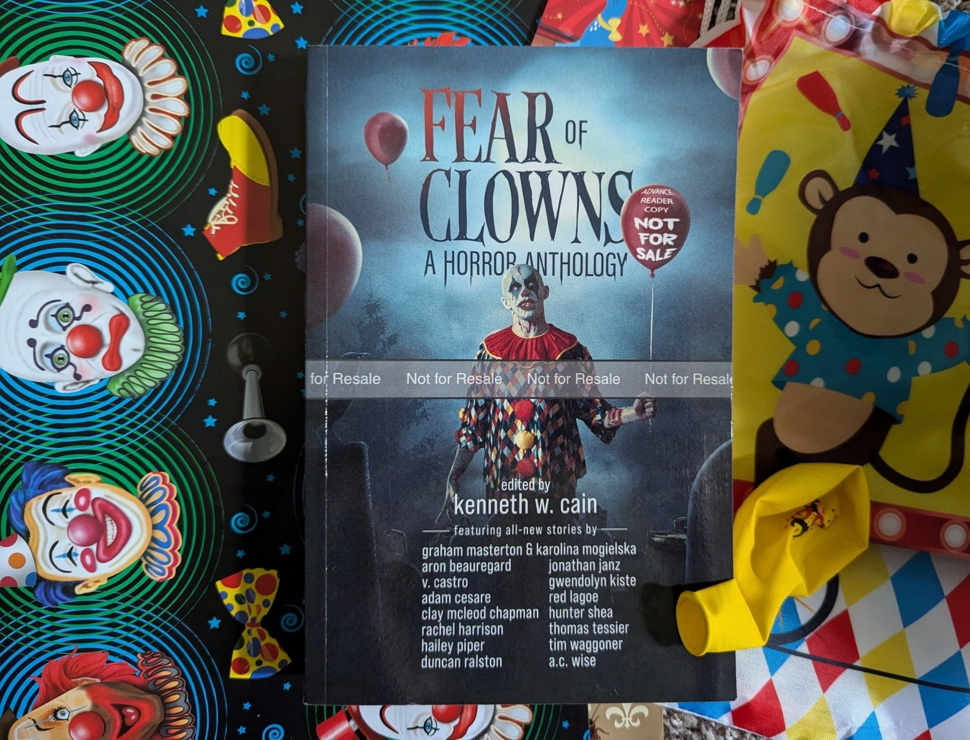 Paperback Advanced Reader Copy of FEAR OF CLOWNS: A HORROR ANTHOLOGY. A creepy clown holds a balloon while standing in a graveyard.