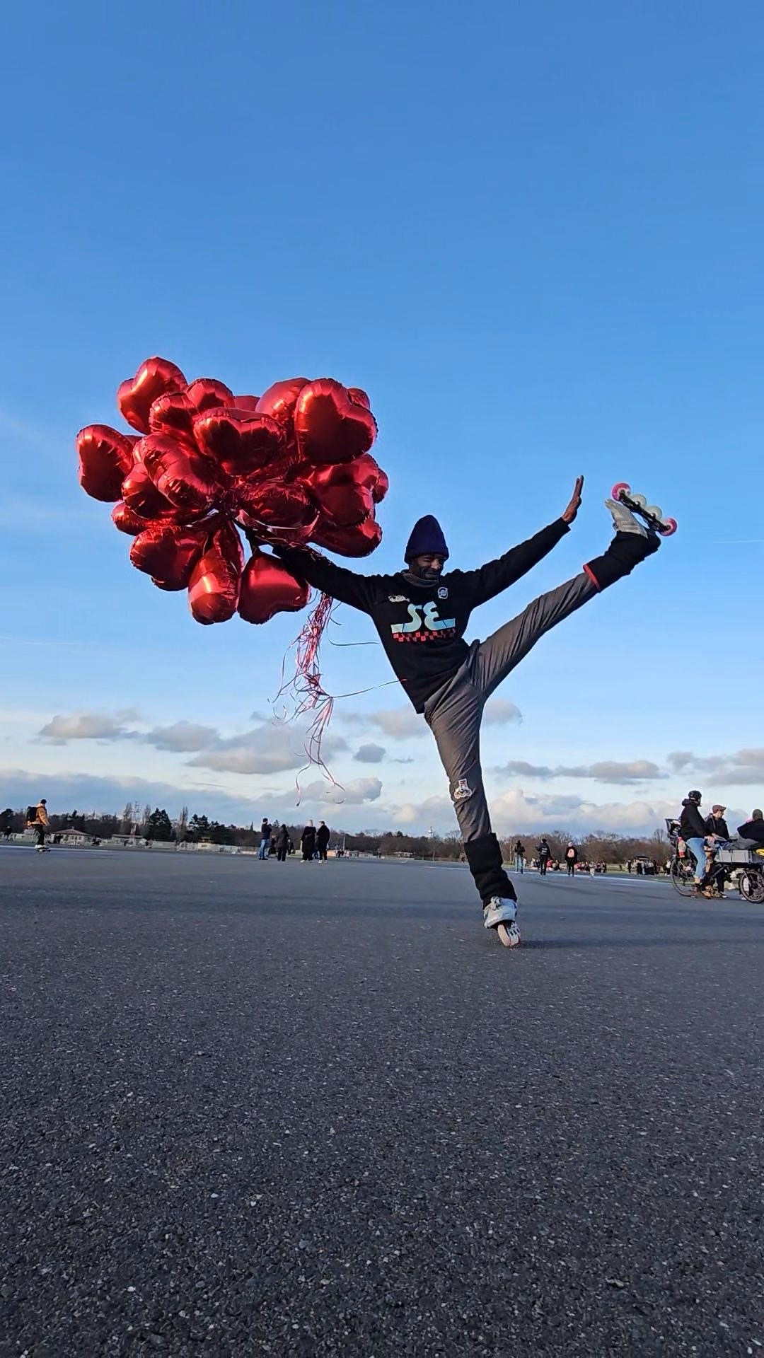 Ein Inlineskater mit einem Strauss Herz-Ballons dreht eine Pirouette 