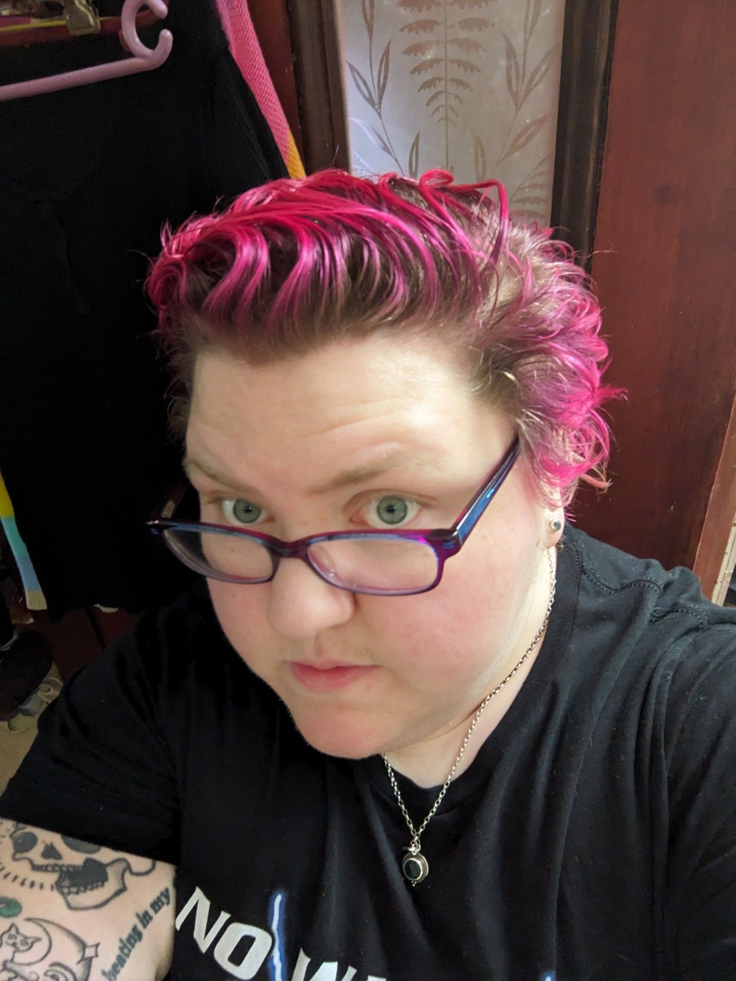 A fat white woman with short hair and a very grown-out pink dyejob looks into the camera.