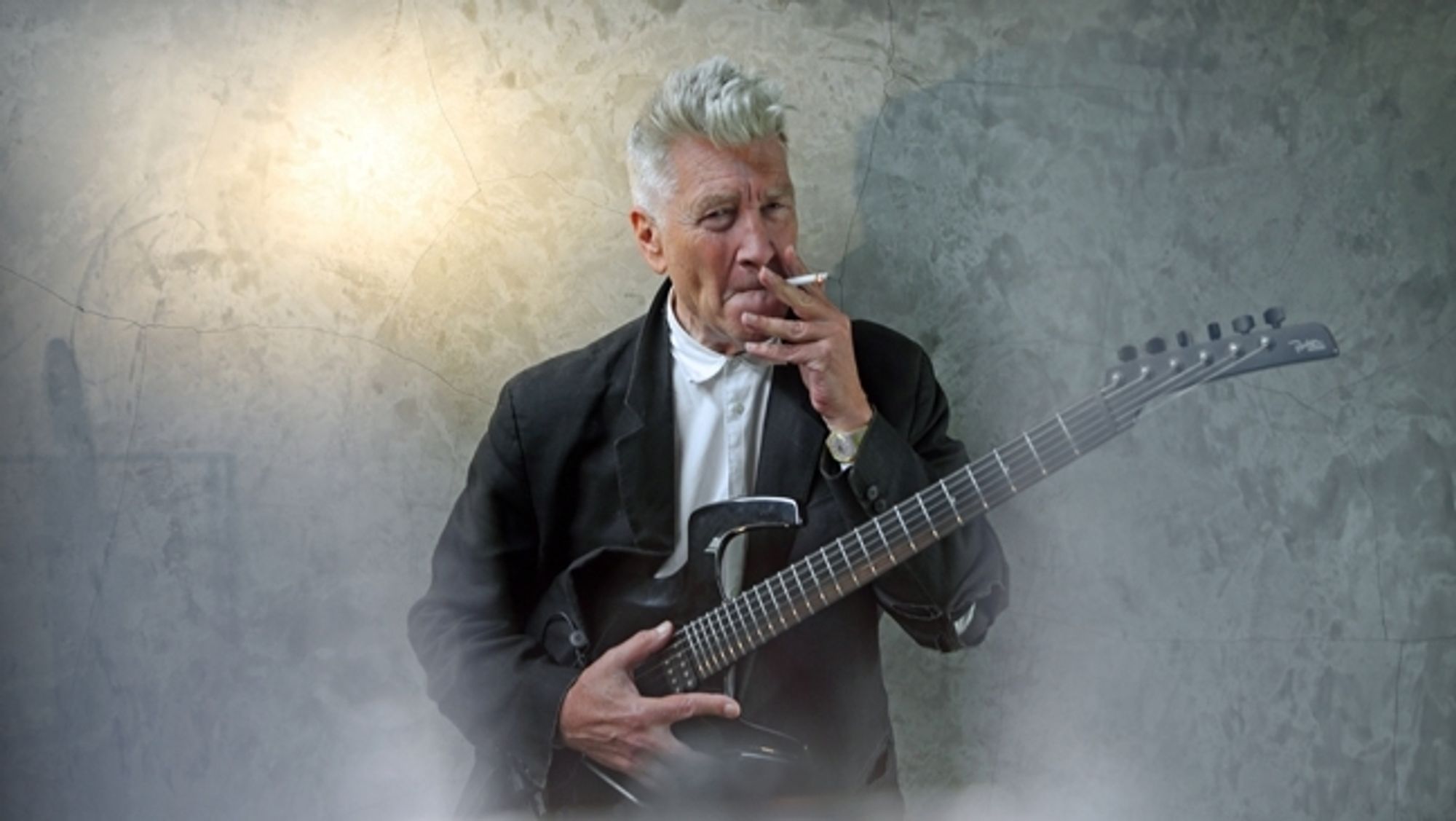 David Lynch smoking a dart and holding a guitar w/an *aggressively* shaped headstock