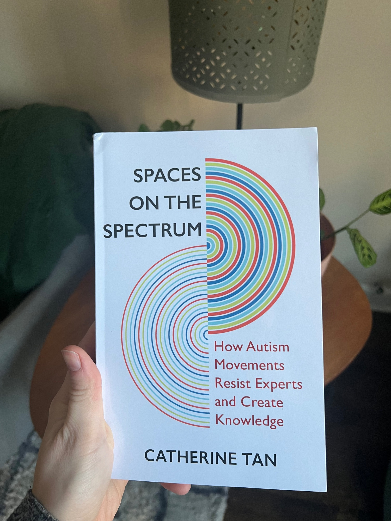 Me holding the book spaces on the spectrum by Catherine Tan