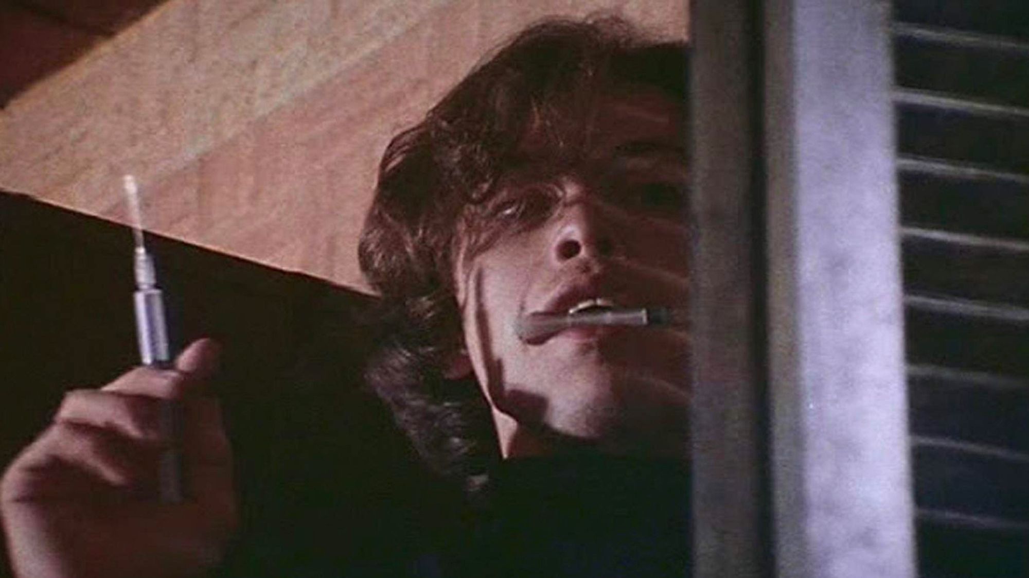 Martin, the title character from George Romero's vampire movie, outside a window with a hypodermic needle in his hand