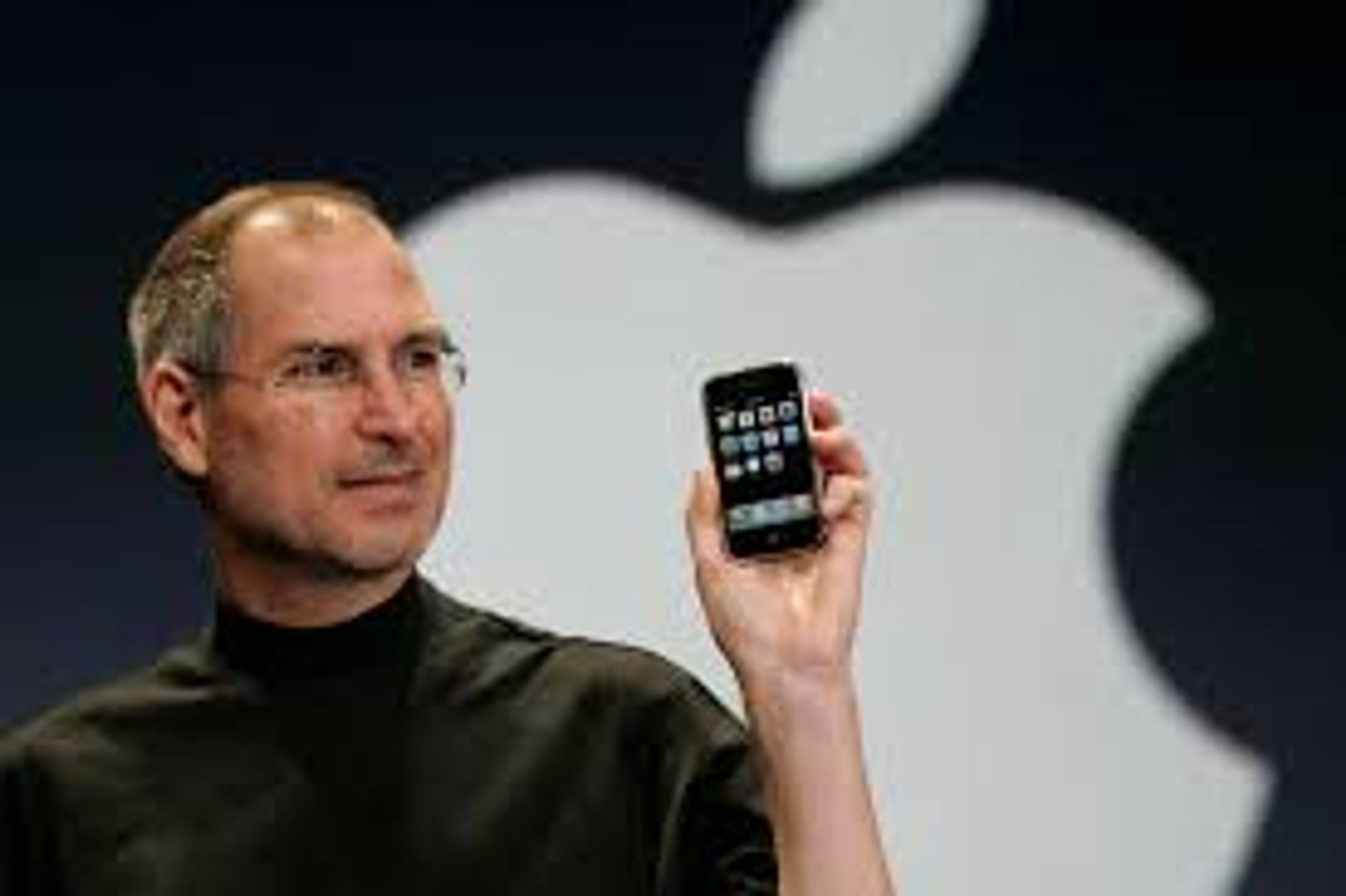 Steve Jobs holding up the first iPhone