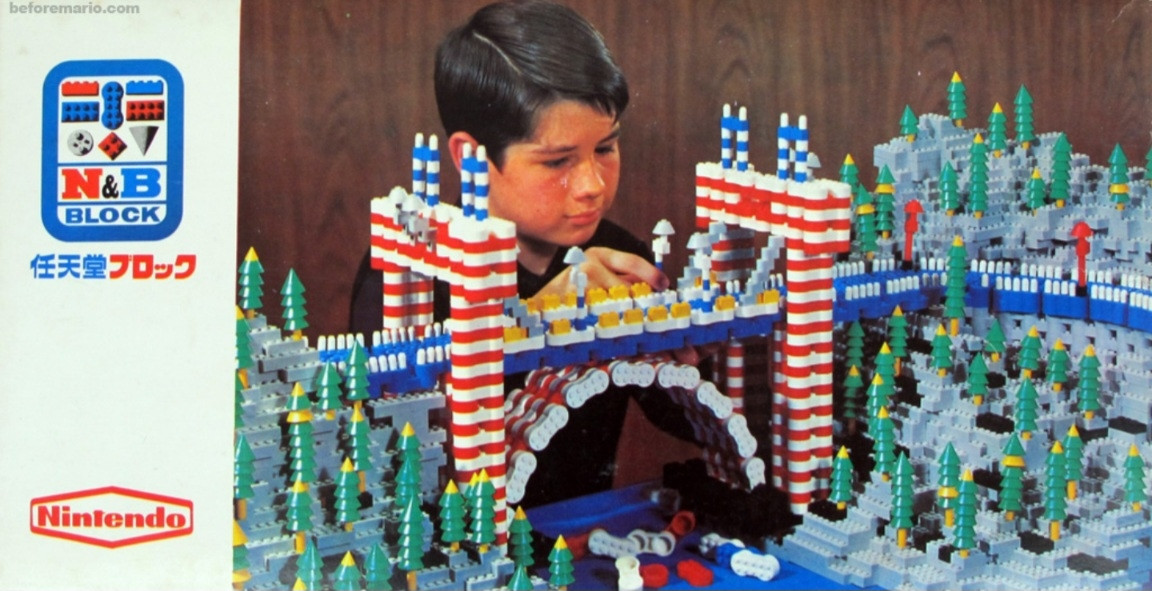 Image of N&B building blocks from the 1960s. A boy looks over a model-train-sized bridge and forest landscape made of N&B bricks. 