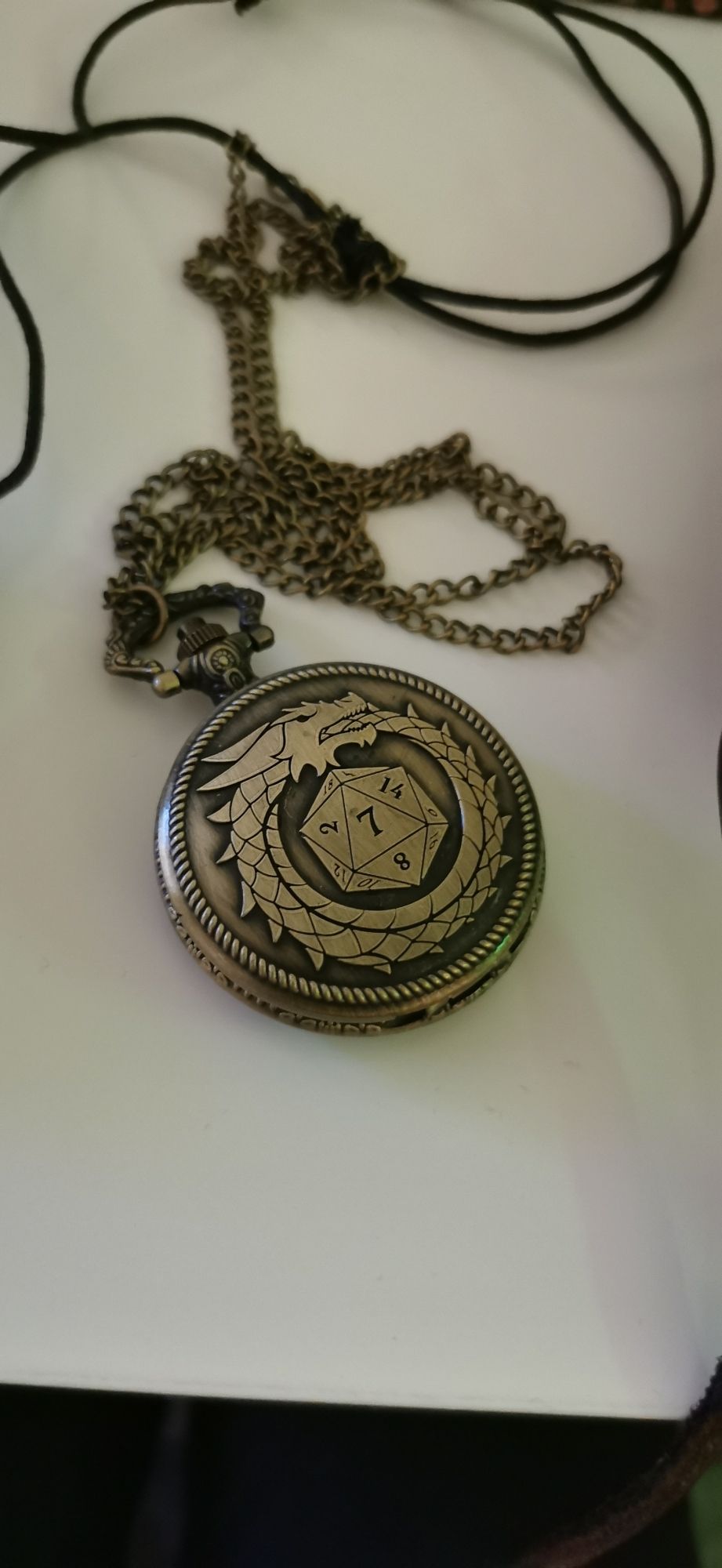 Ein goldenes Medallion mit einem Drachen und einem Würfel drauf