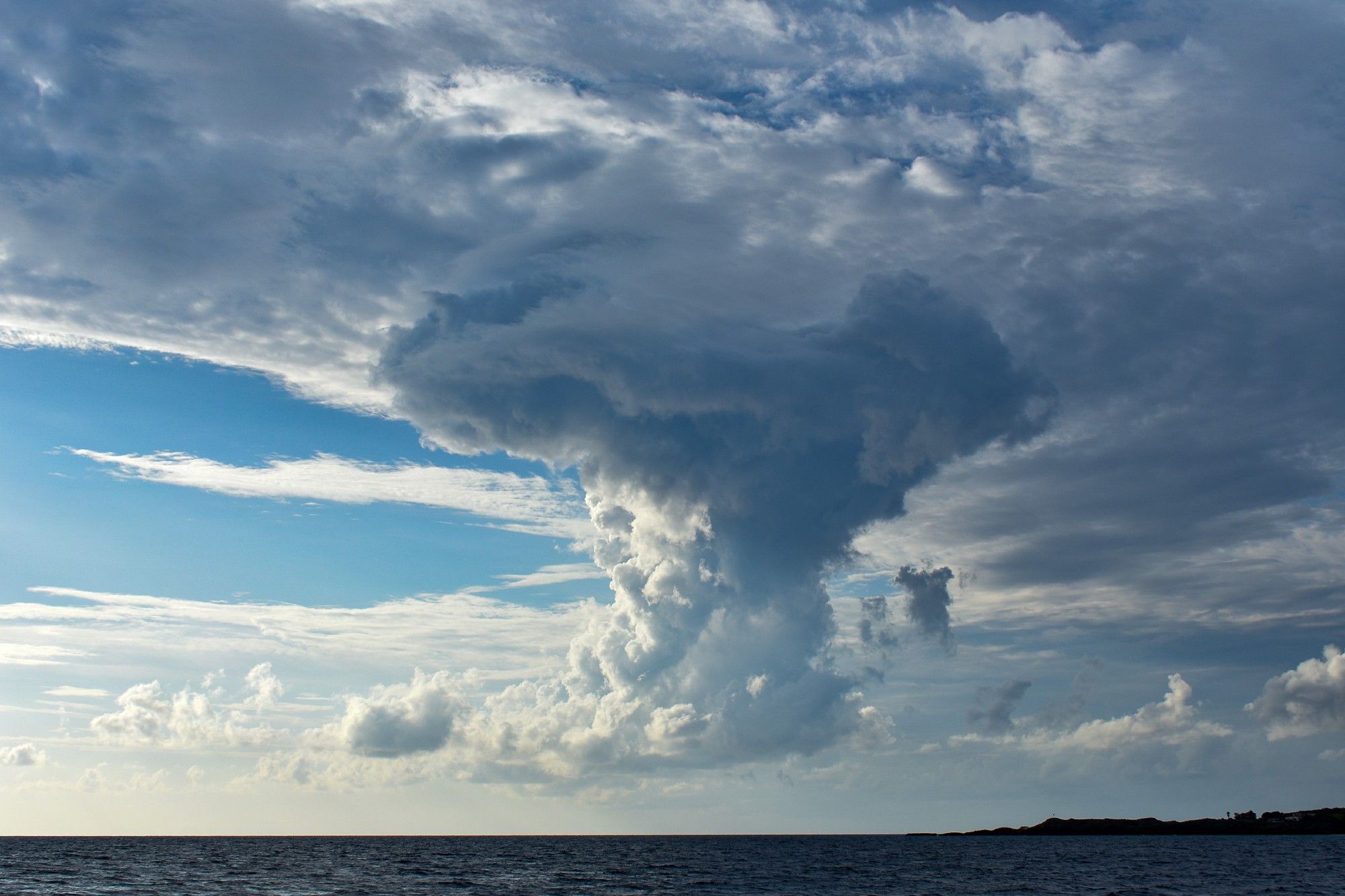 A large cloud billows up from just above the sea.