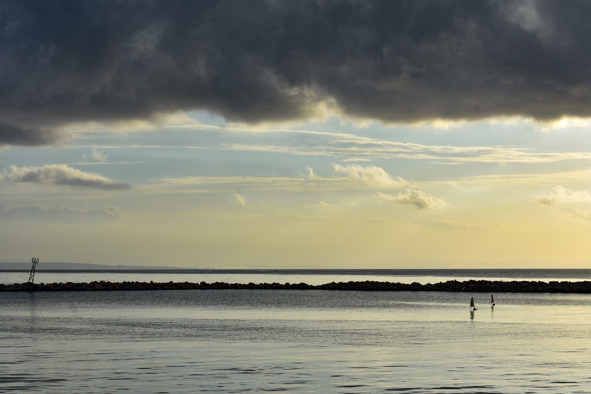 A moody sky over a silent, golden sea overlays the glow of a sunset.