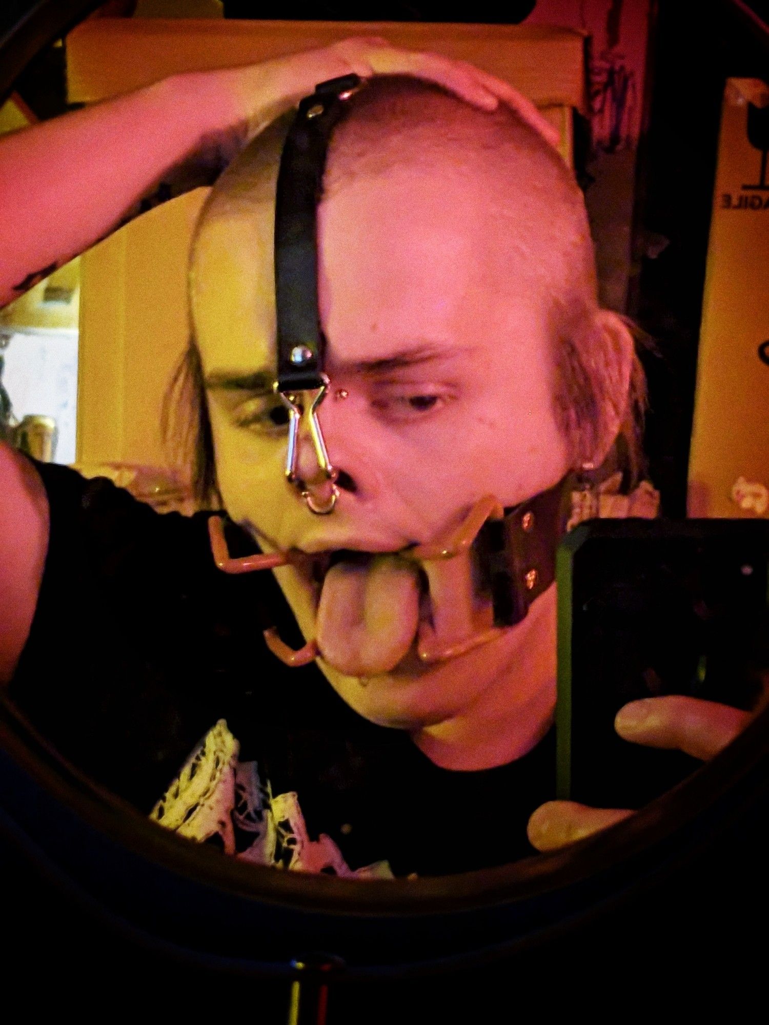 butch trans woman with a buzzcut in a head harness with a nose hook and a mouth separator