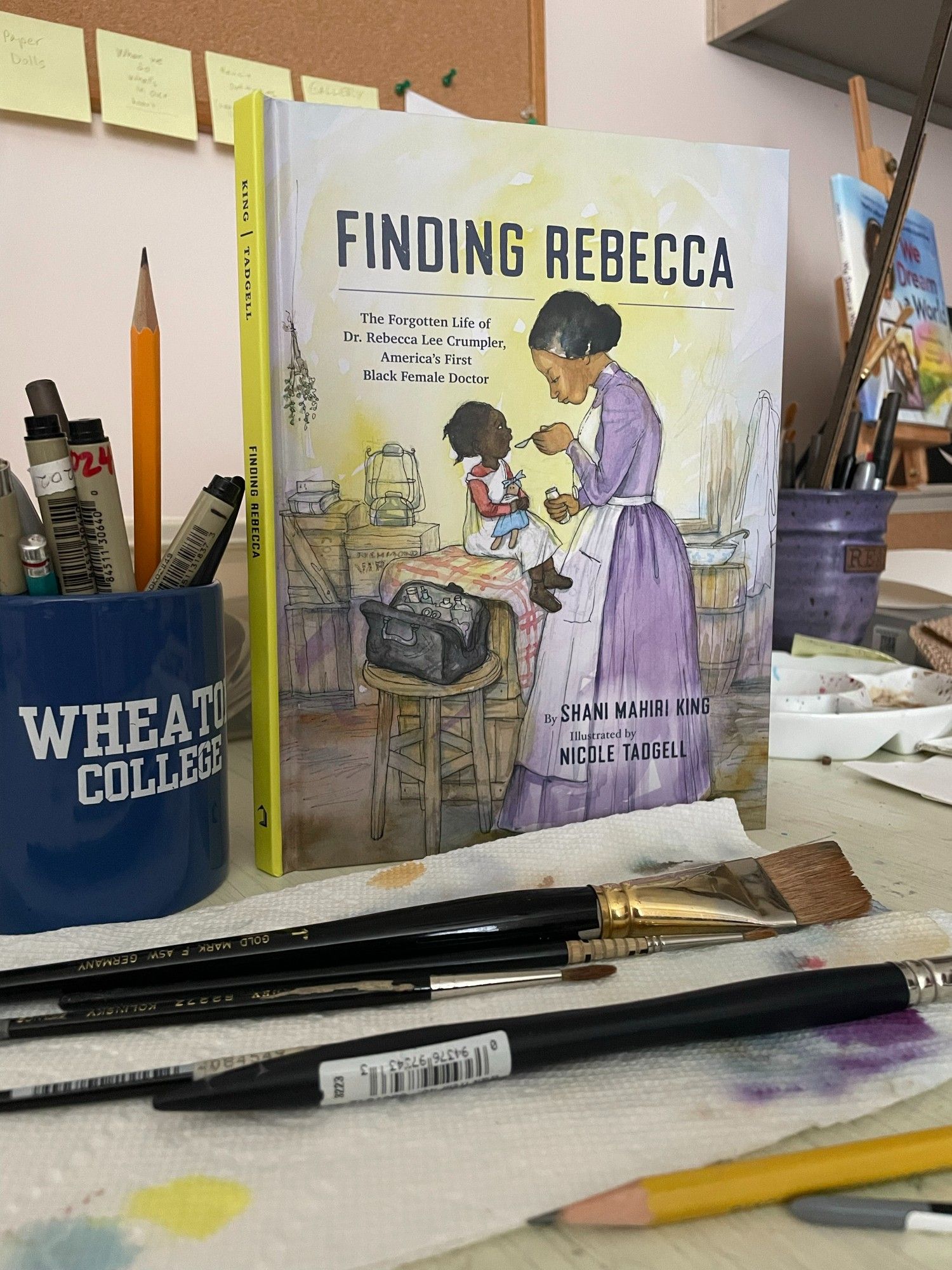 Image of children's book "Finding Rebecca" on a table with art supplies