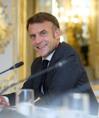 Photo du service de presse du président ukrainien/AFP. Emmanuel Macron est assis à droite de l'image, il regarde vers l'objectif du photographe, on ne sait pas trop s'il sourit. Sur sa tempe, ses cheveux sont complètement poivre et sel, voire gris, alors que sur le dessus ses cheveux sont plutôt marron, roux.