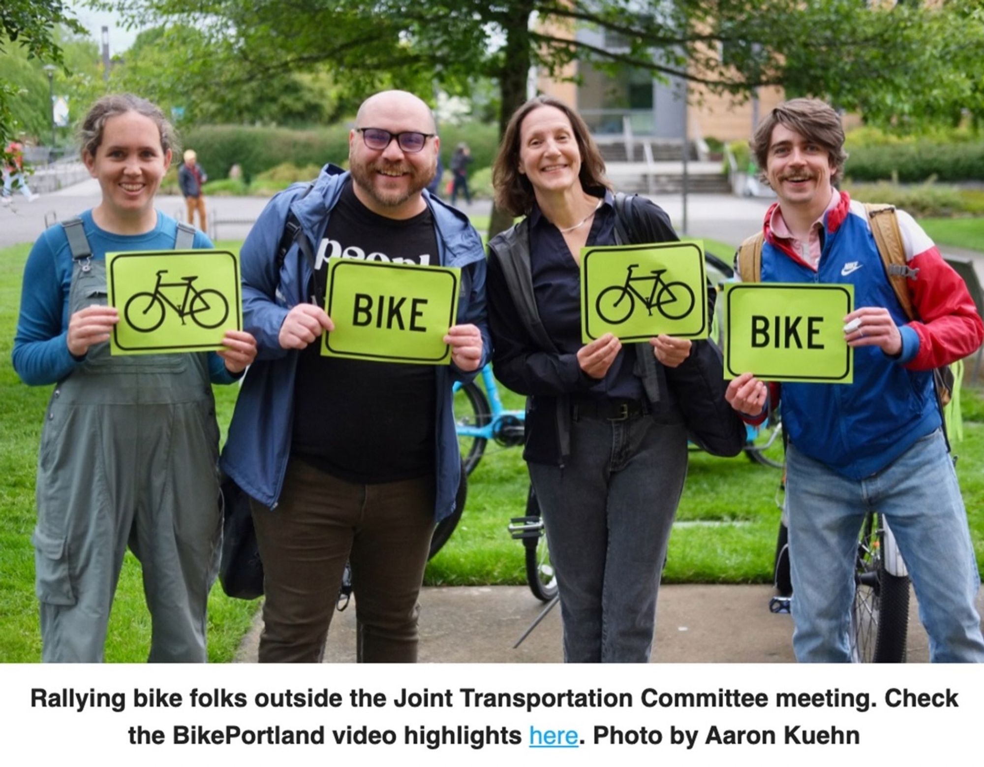 4 people holding signs that have a photo of a bike or the word BIKE on them.