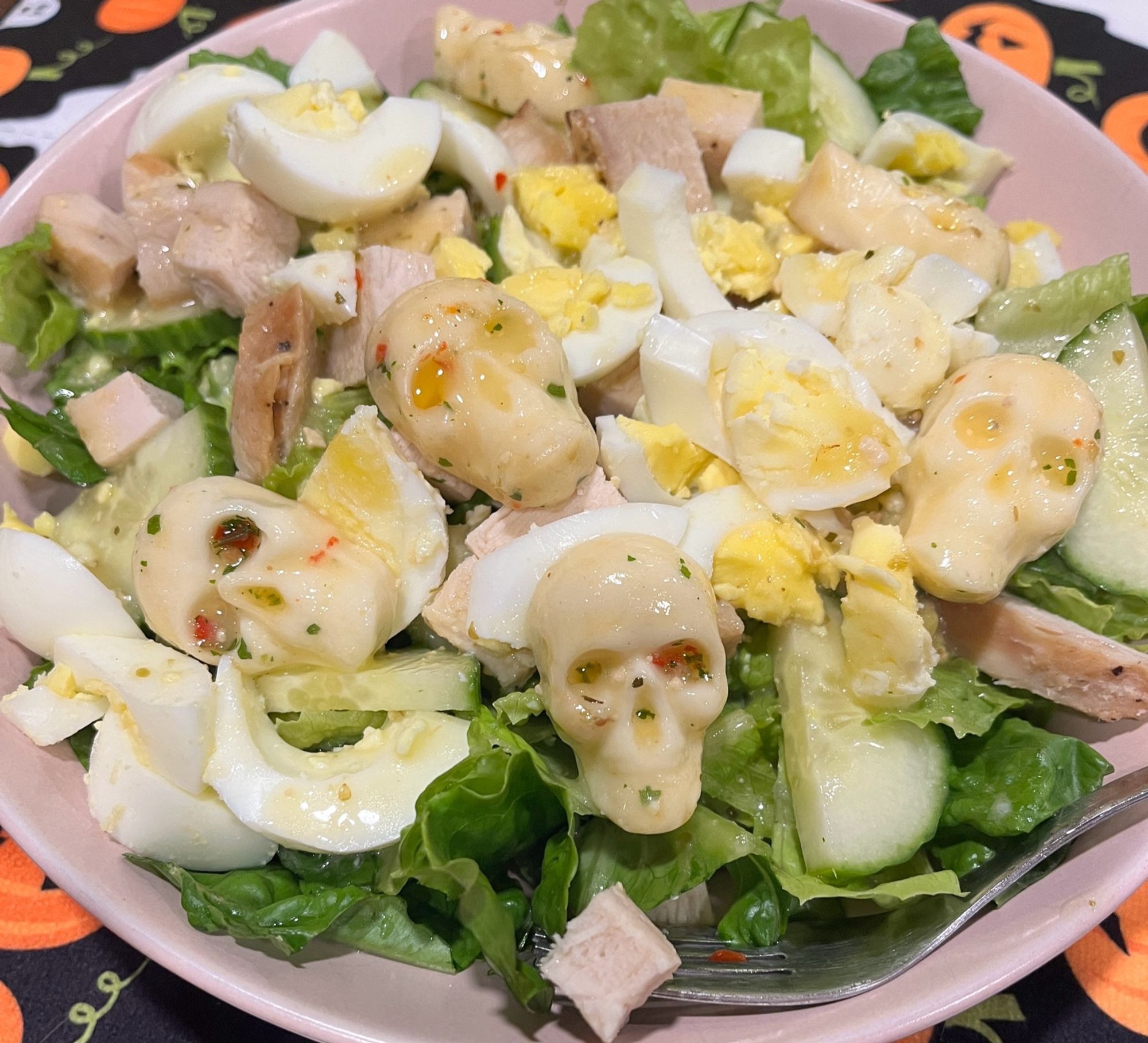 A big Romain lettuce salad with cucumbers, chicken, and cucumbers. It has also been topped with skull shaped mozzarella that I shaped myself