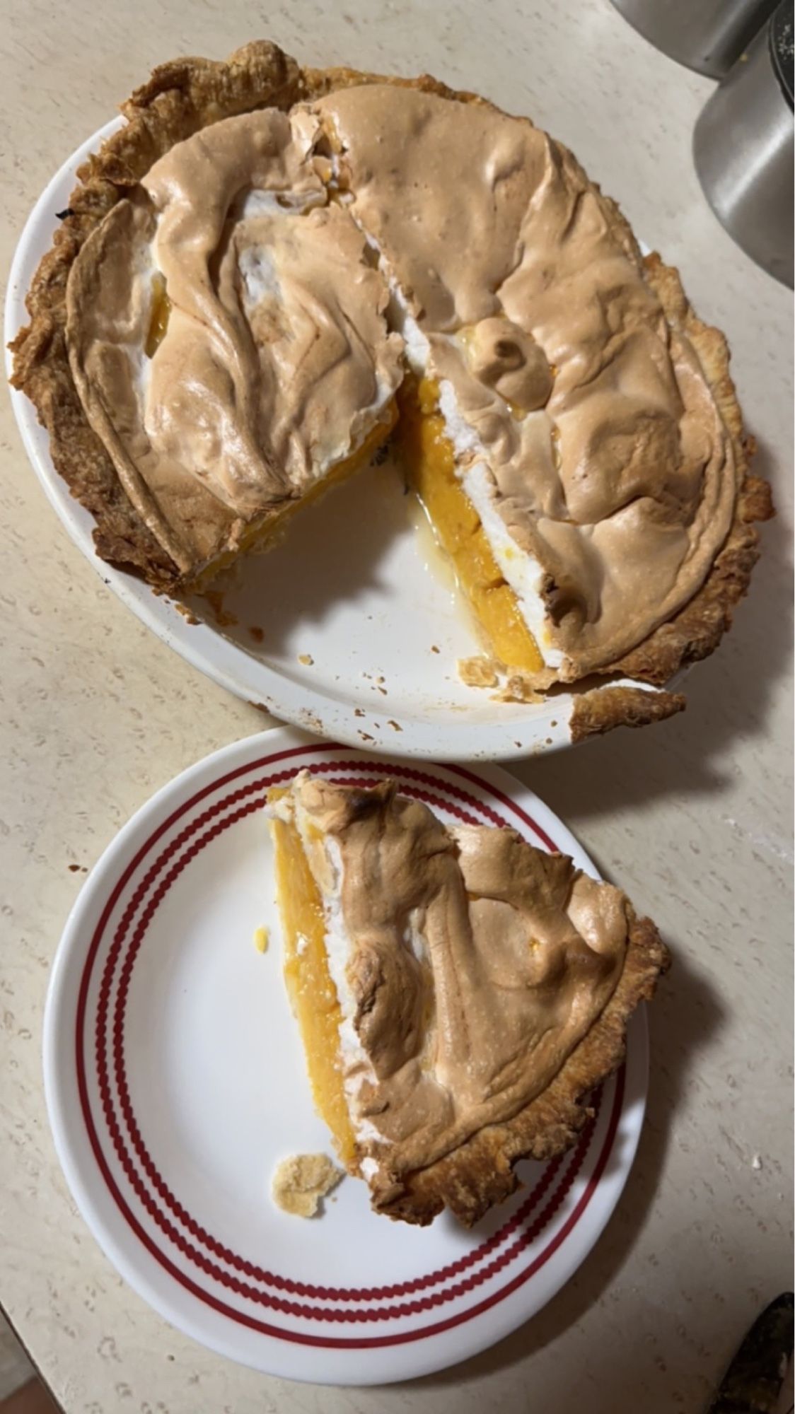 A cantaloupe pie with a slice removed and that slice on a plate. The pie is orange with meringue on top.