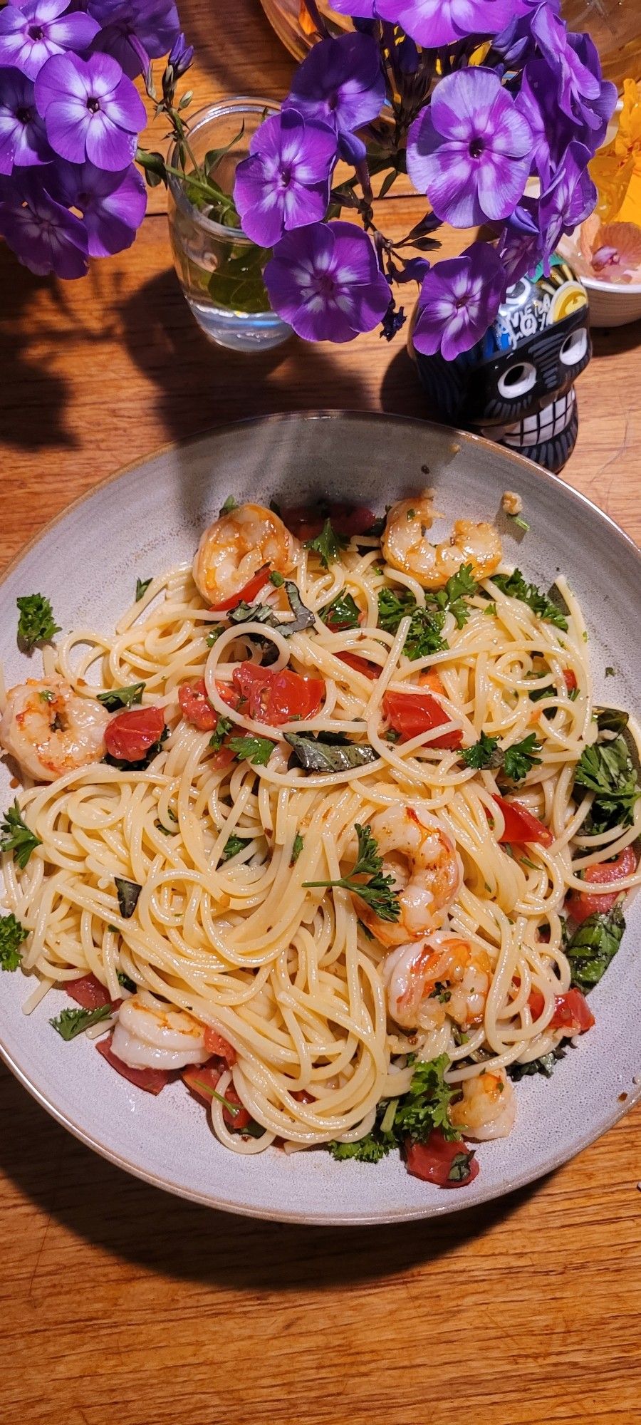 Spaghetti with butter, garlic, cherry tomatoes and shrimp, garnished with parsley and basil.