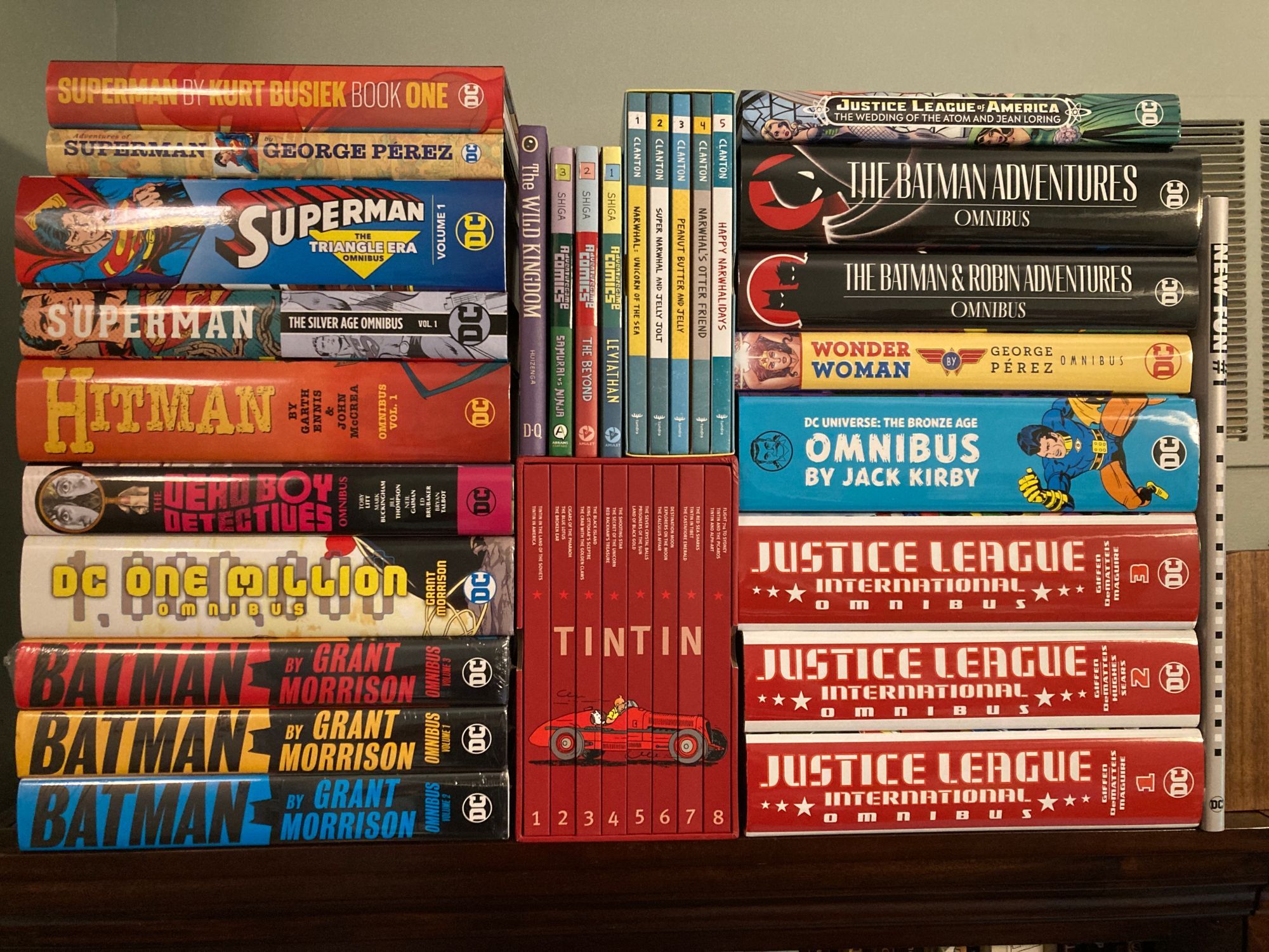 Lots of hardcover comics, mostly DC omnibuses (incl. Morrison's Batman & DC One Million, Hitman, Superman Silver Age and Triangle Era, Batman Adventures, Wonder Woman by Pérez, Bronze Age by Jack Kirby, and JLI); also some Tintin, Jason Shiga, and more