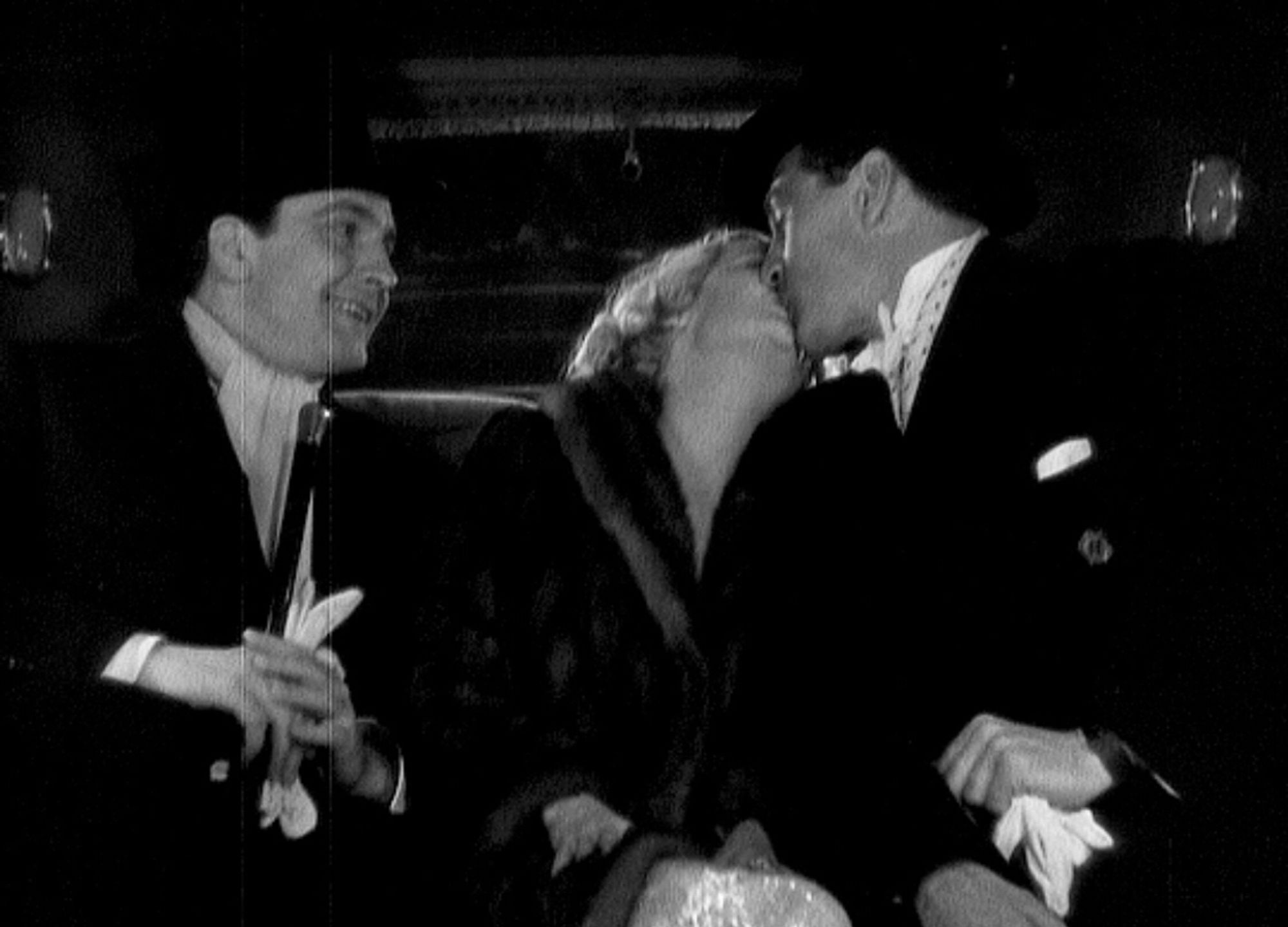 Miriam Hopkins kissing Gary Cooper as a smiling Frederic March looks on, from the 1933 throuple movie Design For Living