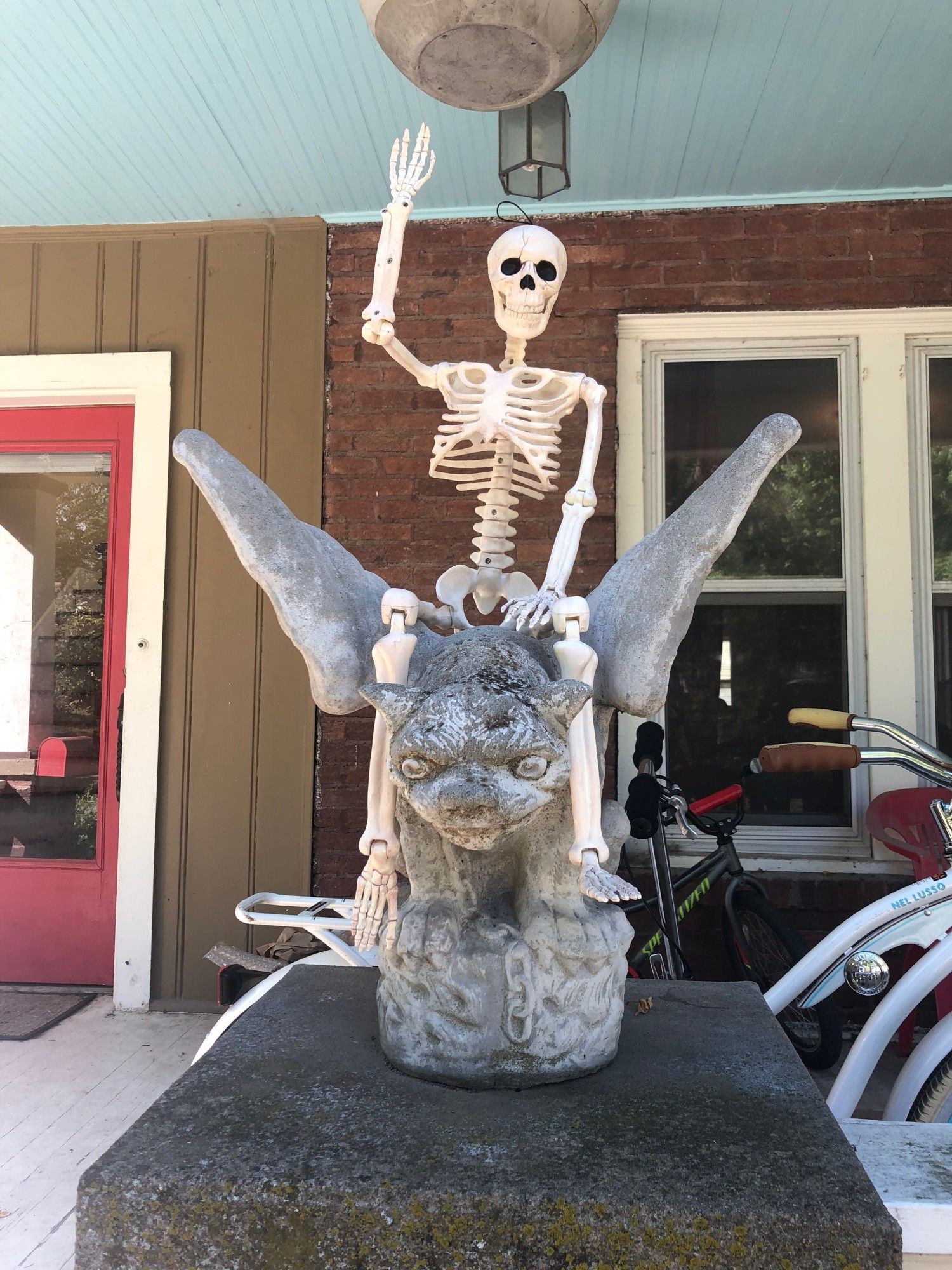 A plastic skeleton riding on top of a gargoyle.