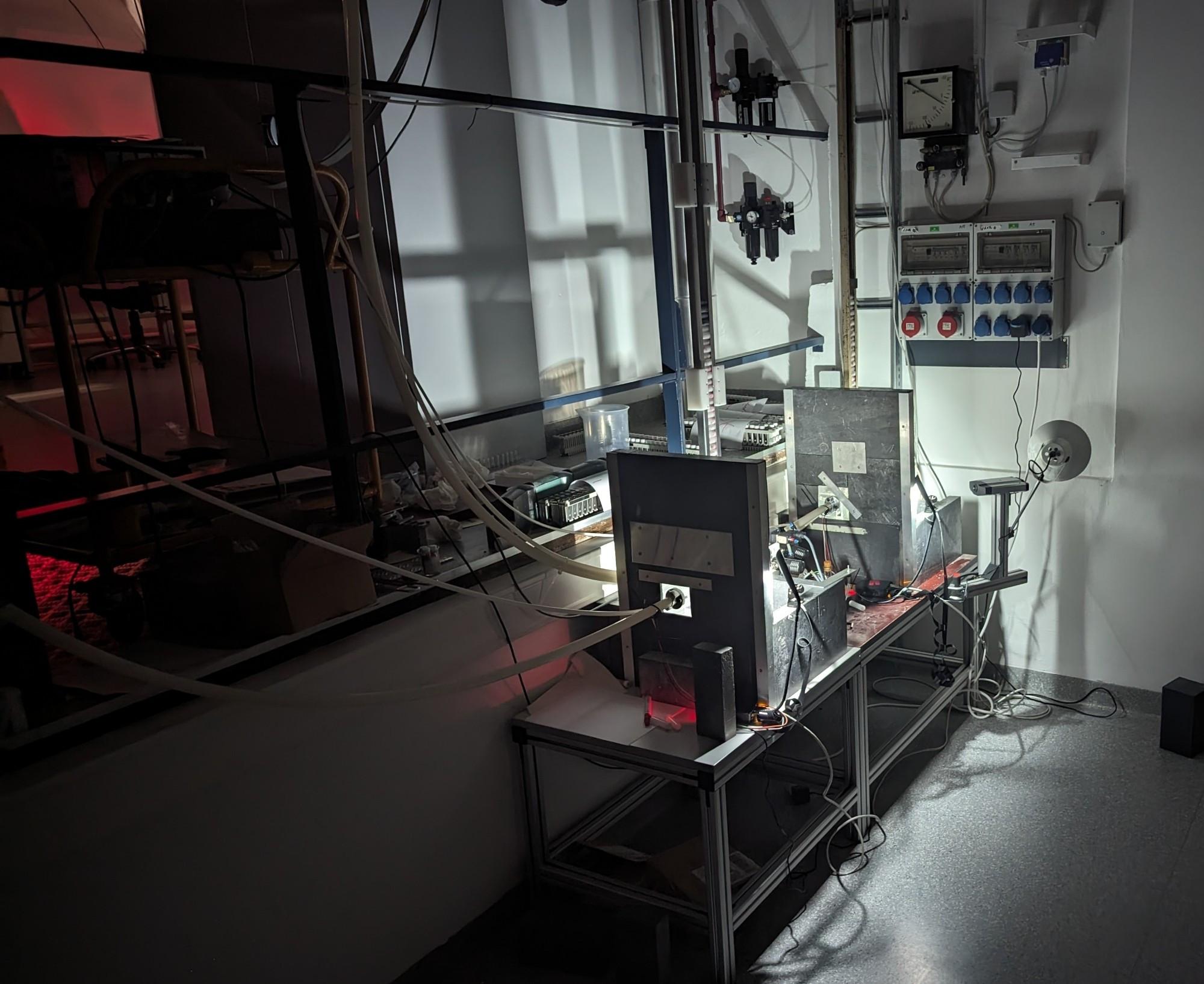 Two lead shields that are brightly lit in an otherwise dark laboratory with cables and pipes leading away